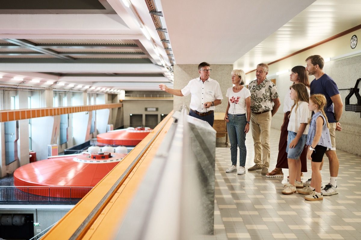 Tourguide mit Besuchergruppe in der Maschinenhalle des Donaukraftwerks Ybbs-Persenbeug bei der Erklärung der Stromerzeugung aus Wasserkraft.