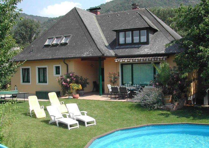 Ein Haus mit Garten, Pool und Liegestühlen.
