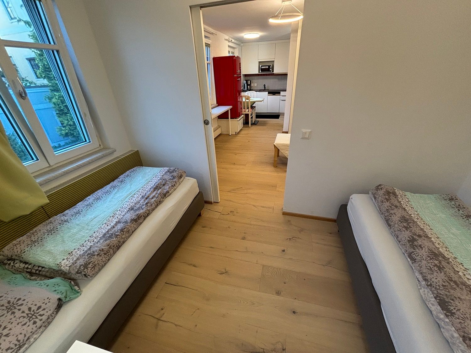 Schlafzimmer mit zwei Einzelbetten und Blick in die Küche.