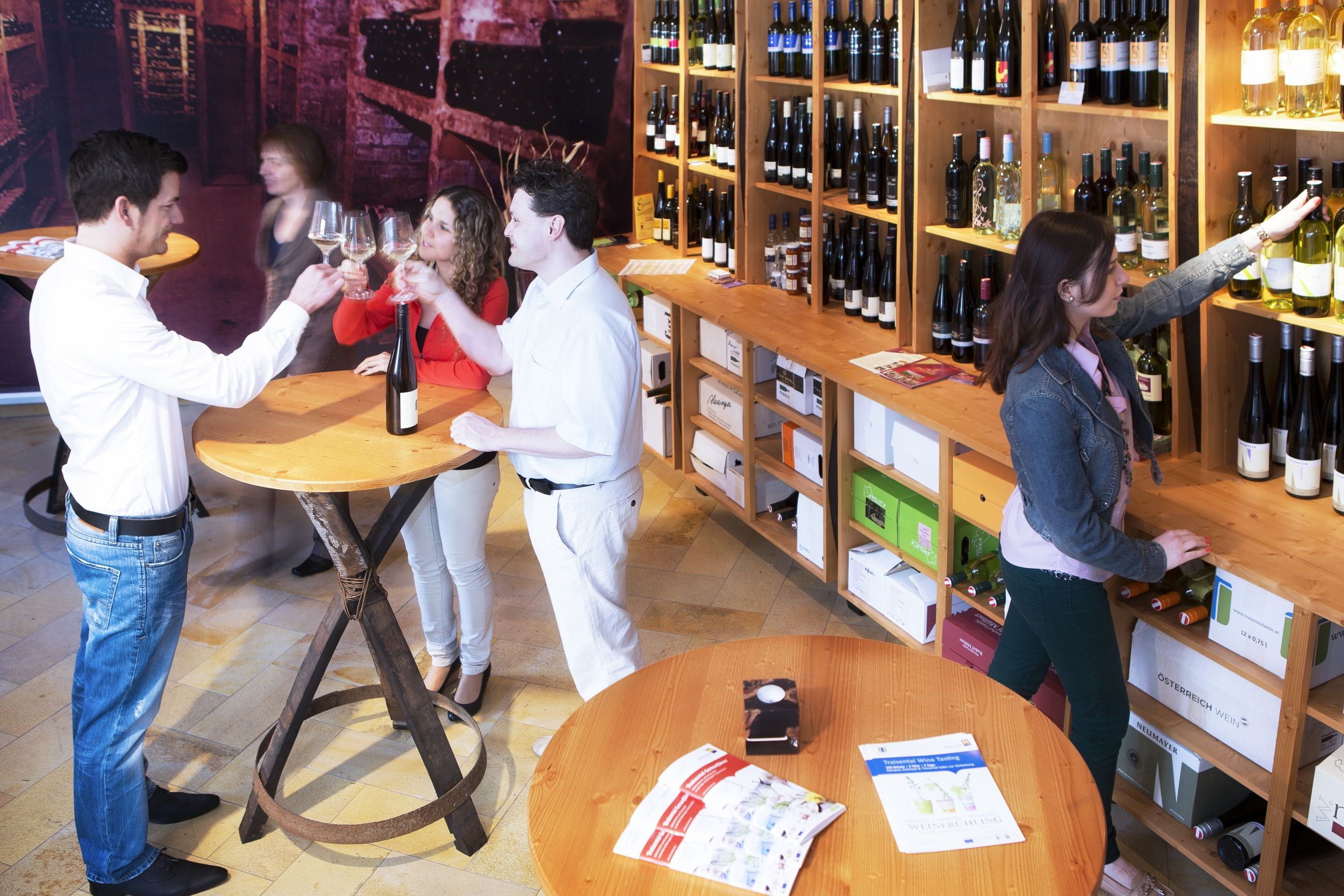 Menschen in einem Weinladen, die Wein probieren und Flaschen auswählen.