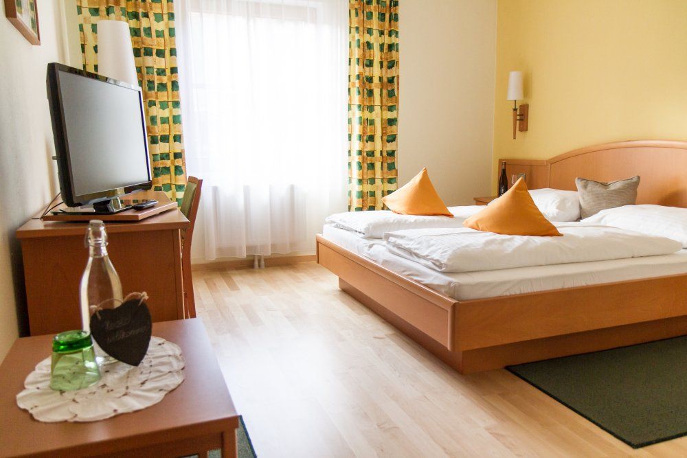 Gemütliches Hotelzimmer mit Doppelbett, Fernseher und Vorhängen.