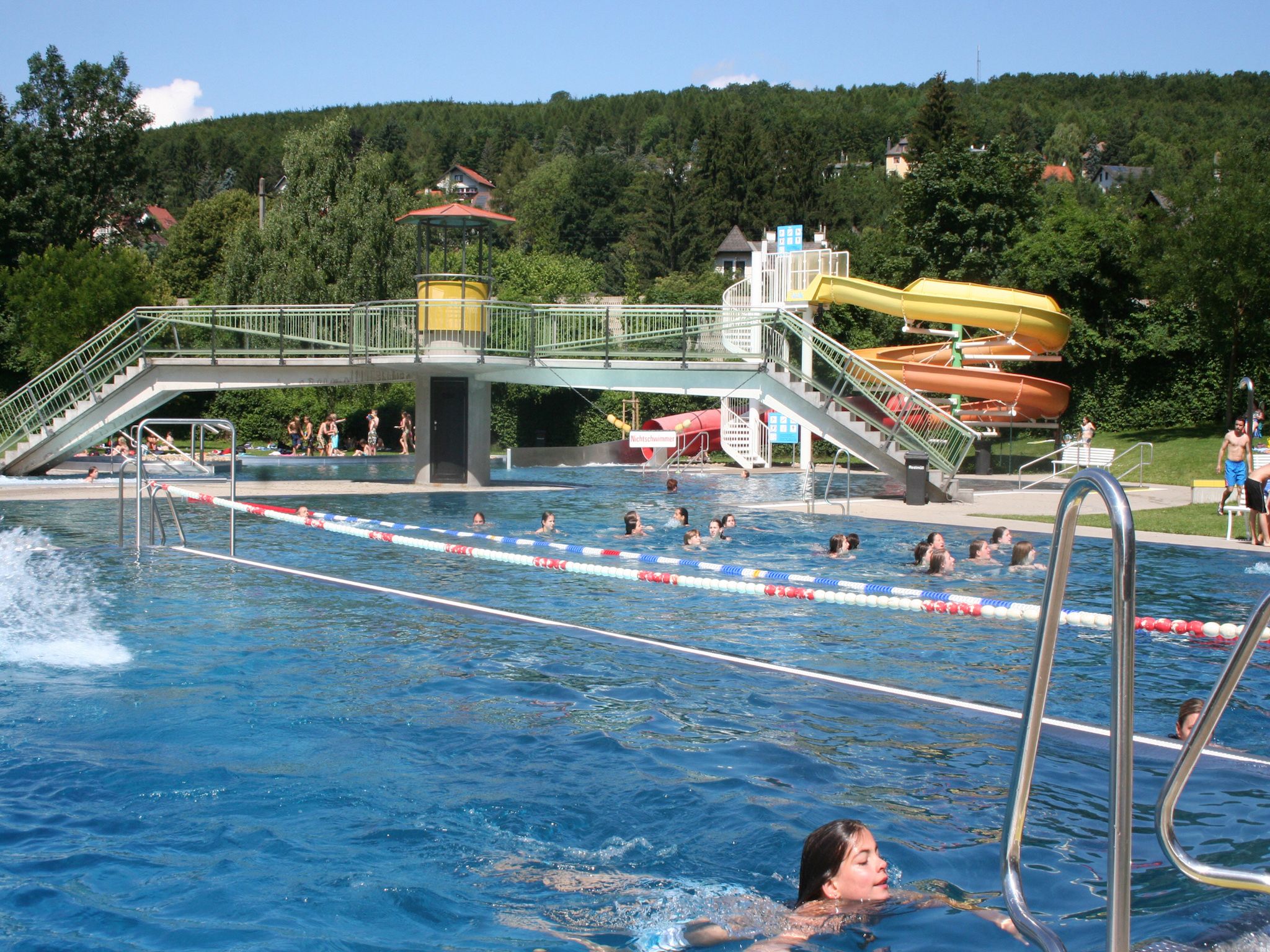 Freibad mit Schwimmern, Rutsche und Brücke im Wienerwaldbad Purkersdorf.