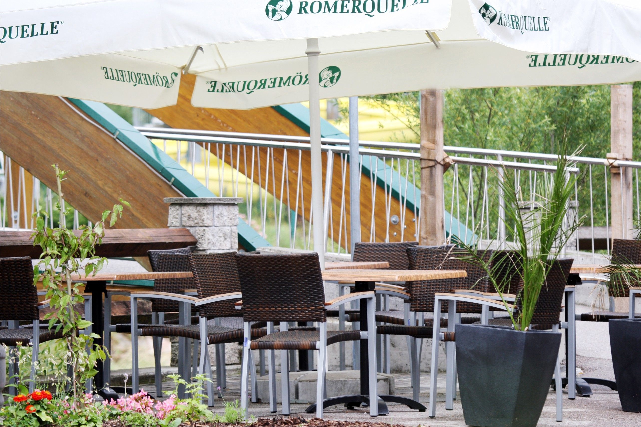 Gemütliche Terrasse mit Tischen, Stühlen und Sonnenschirmen.
