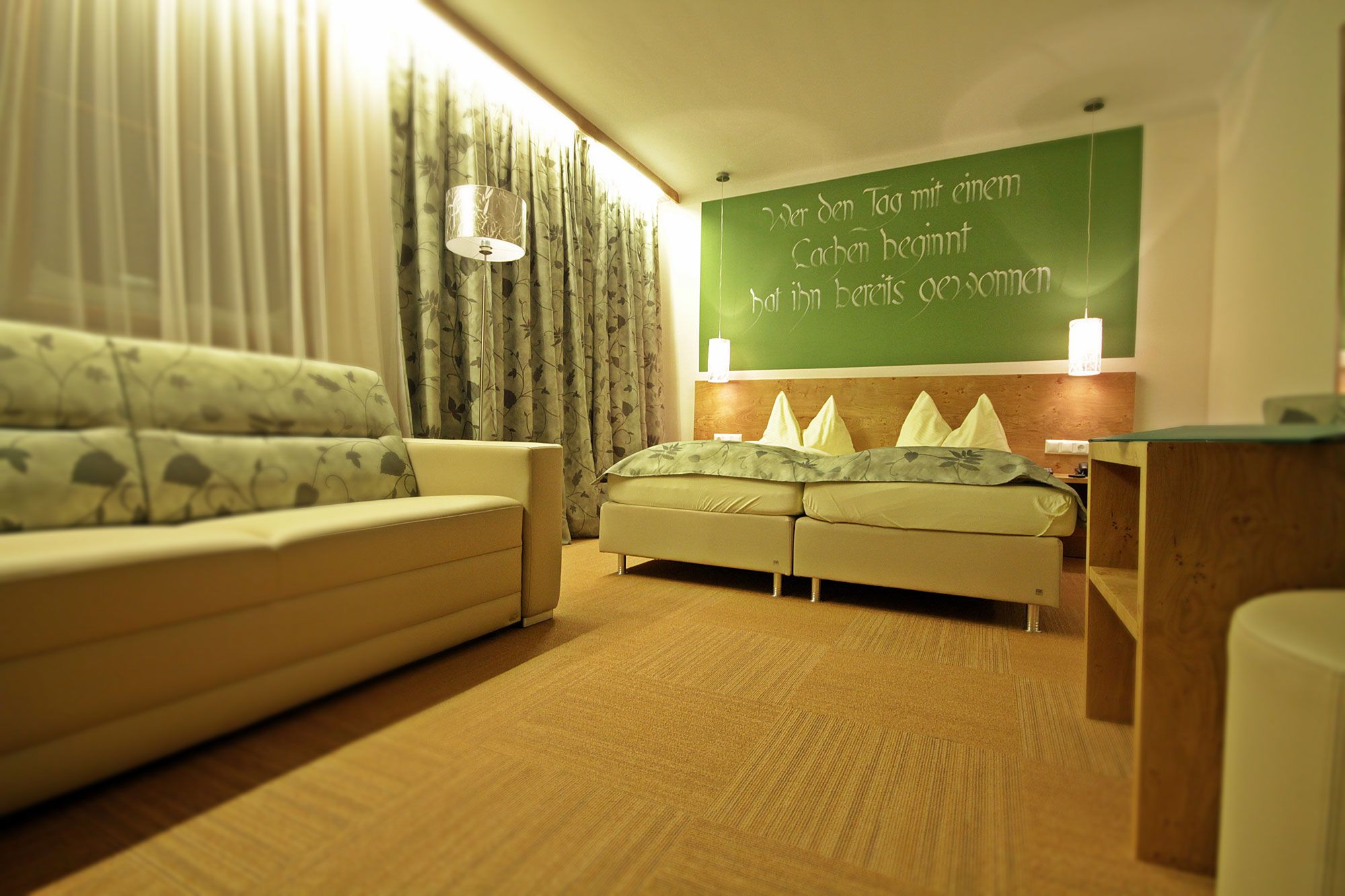 Gemütliches Gästezimmer mit Doppelbett, Sofa und dekorativen Vorhängen.