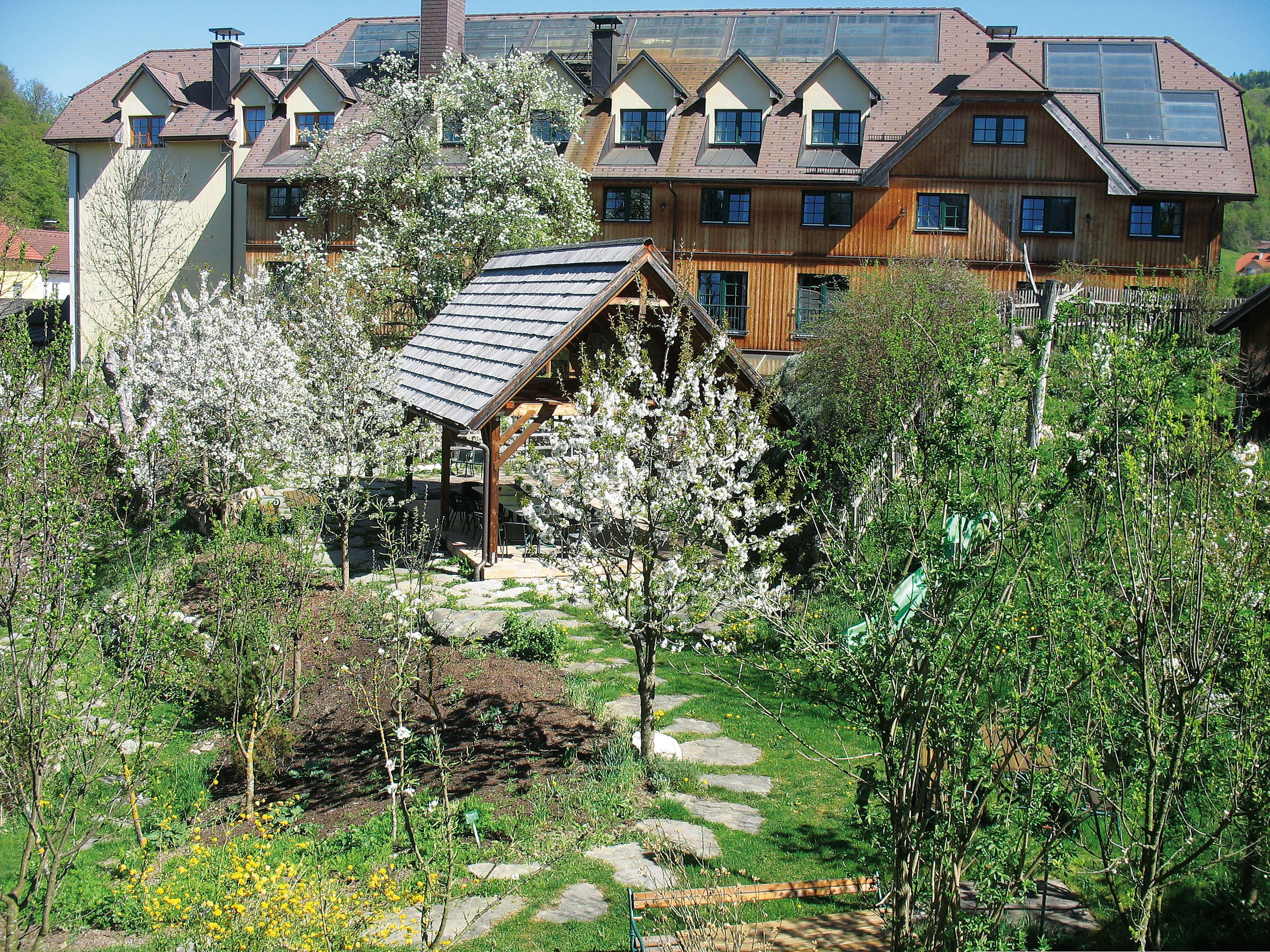 Ein Hotel im Dirndltal mit blühenden Bäumen und Garten.