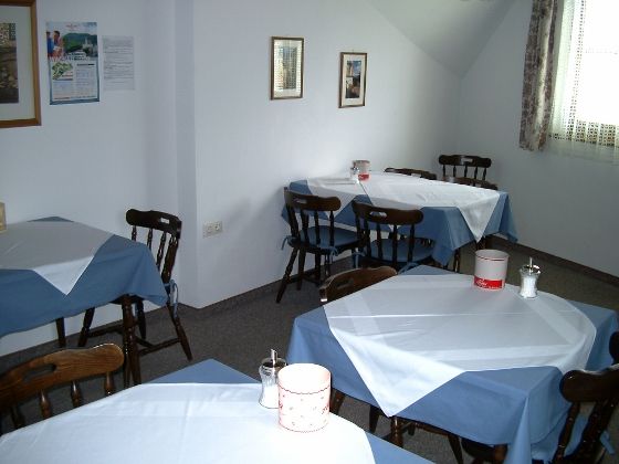Ein Frühstücksraum mit mehreren Tischen, die mit blauen und weißen Tischdecken gedeckt sind.