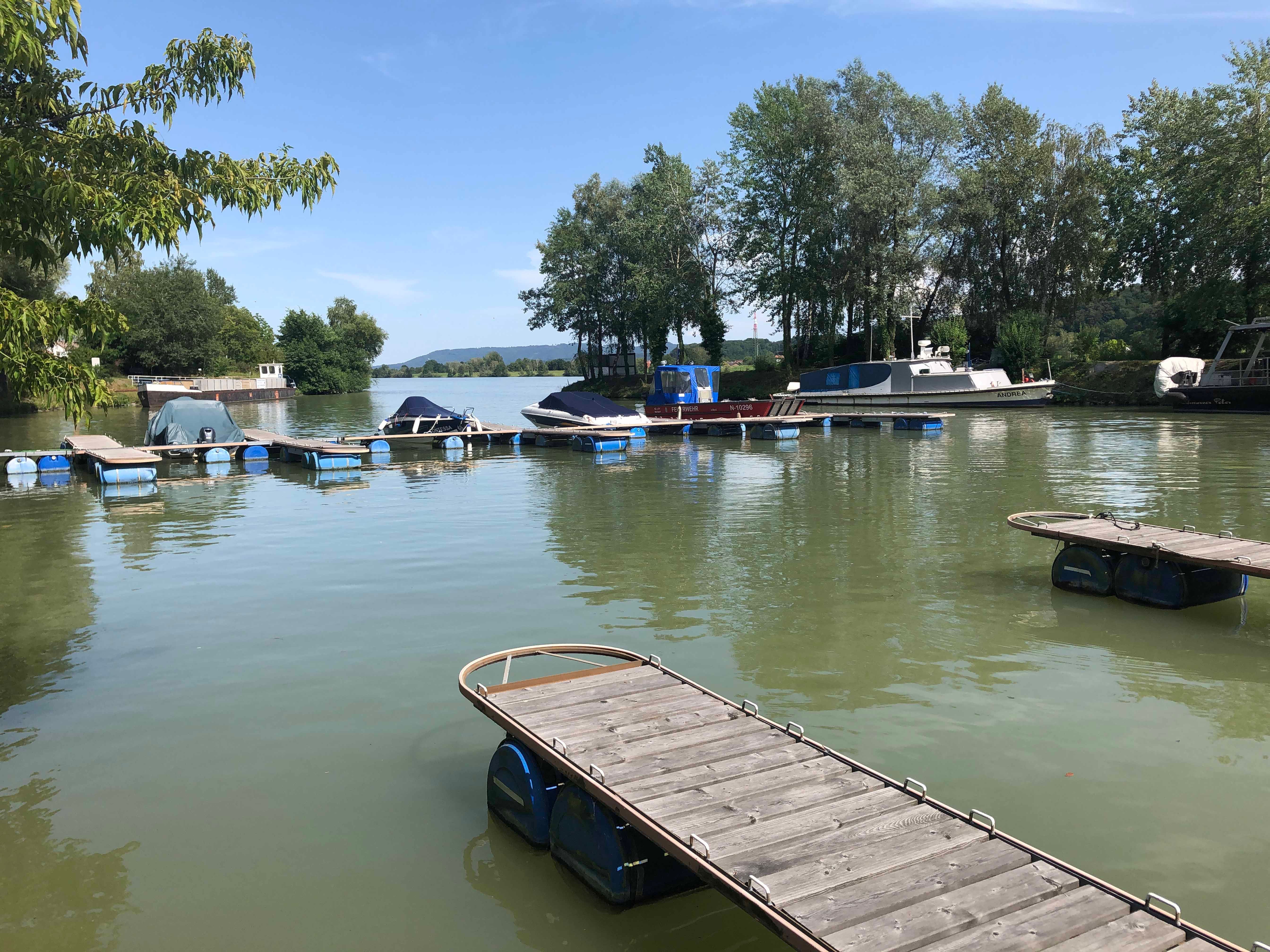 Boote im Hafen von Marbach am Neckar, umgeben von Bäumen und Stegen.