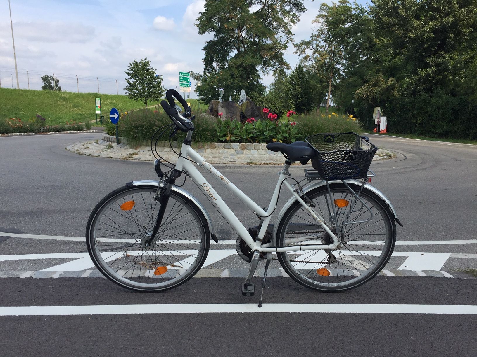 Fahrrad auf einer Straße vor einem Kreisverkehr in Tulln, umgeben von Blumen und Bäumen.