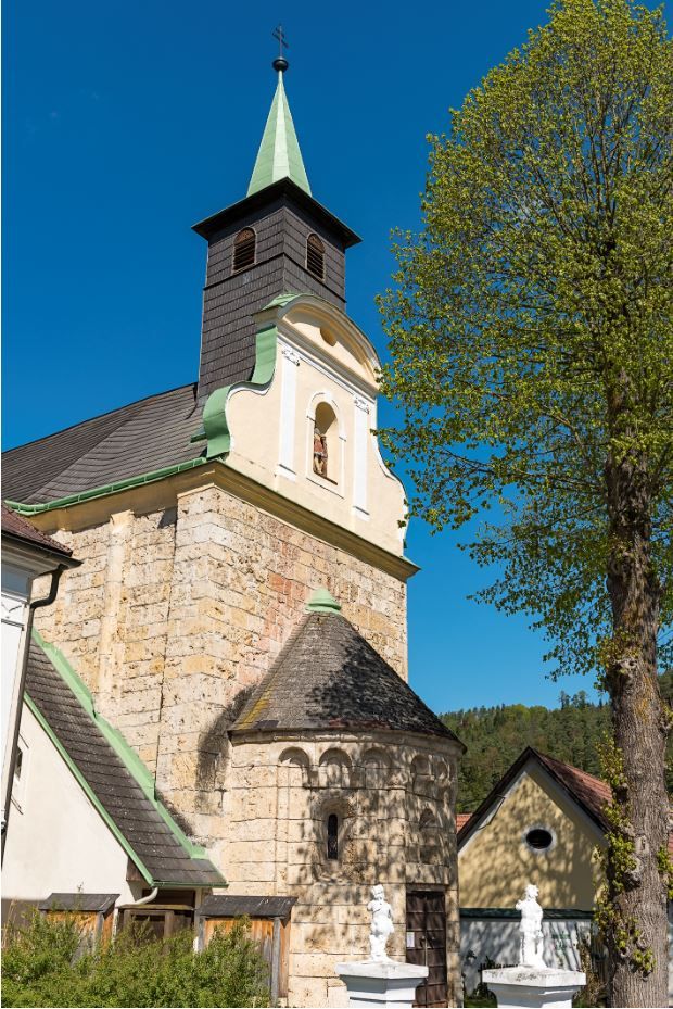 Pfarrkirche Thernberg mit Turm und Baum im Vordergrund.