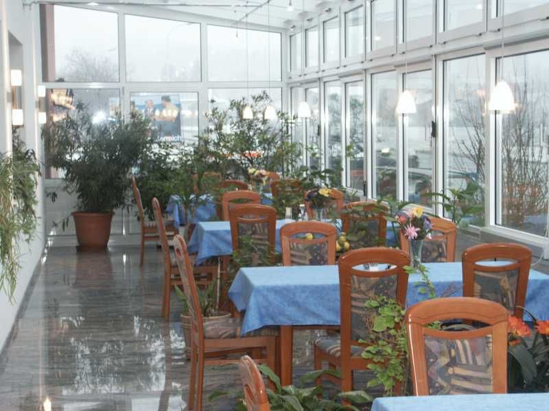 Ein Wintergarten mit Tischen, blauen Tischdecken und vielen Pflanzen.