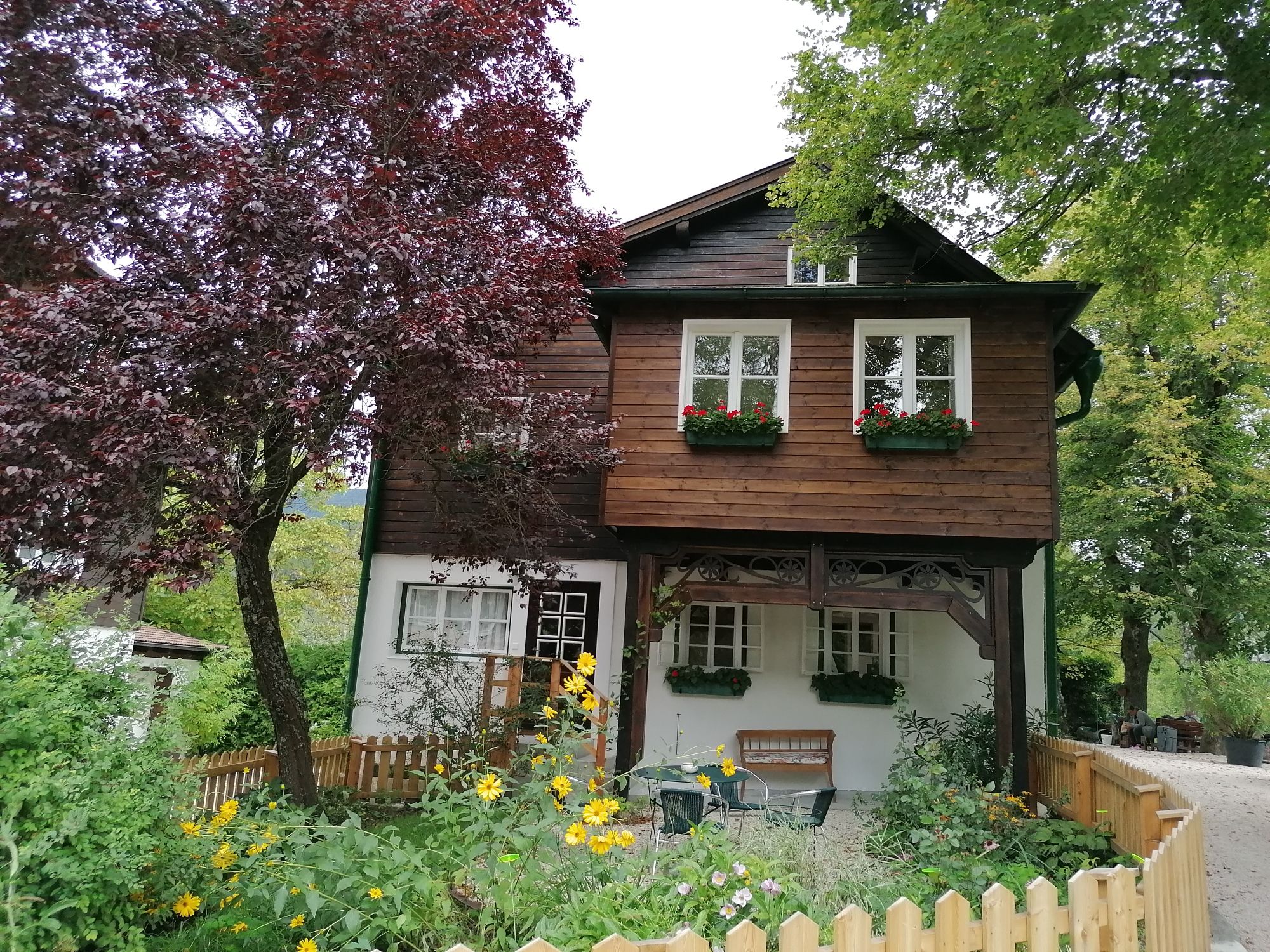 Ein zweistöckiges Holzhaus mit Blumenkästen und Garten.