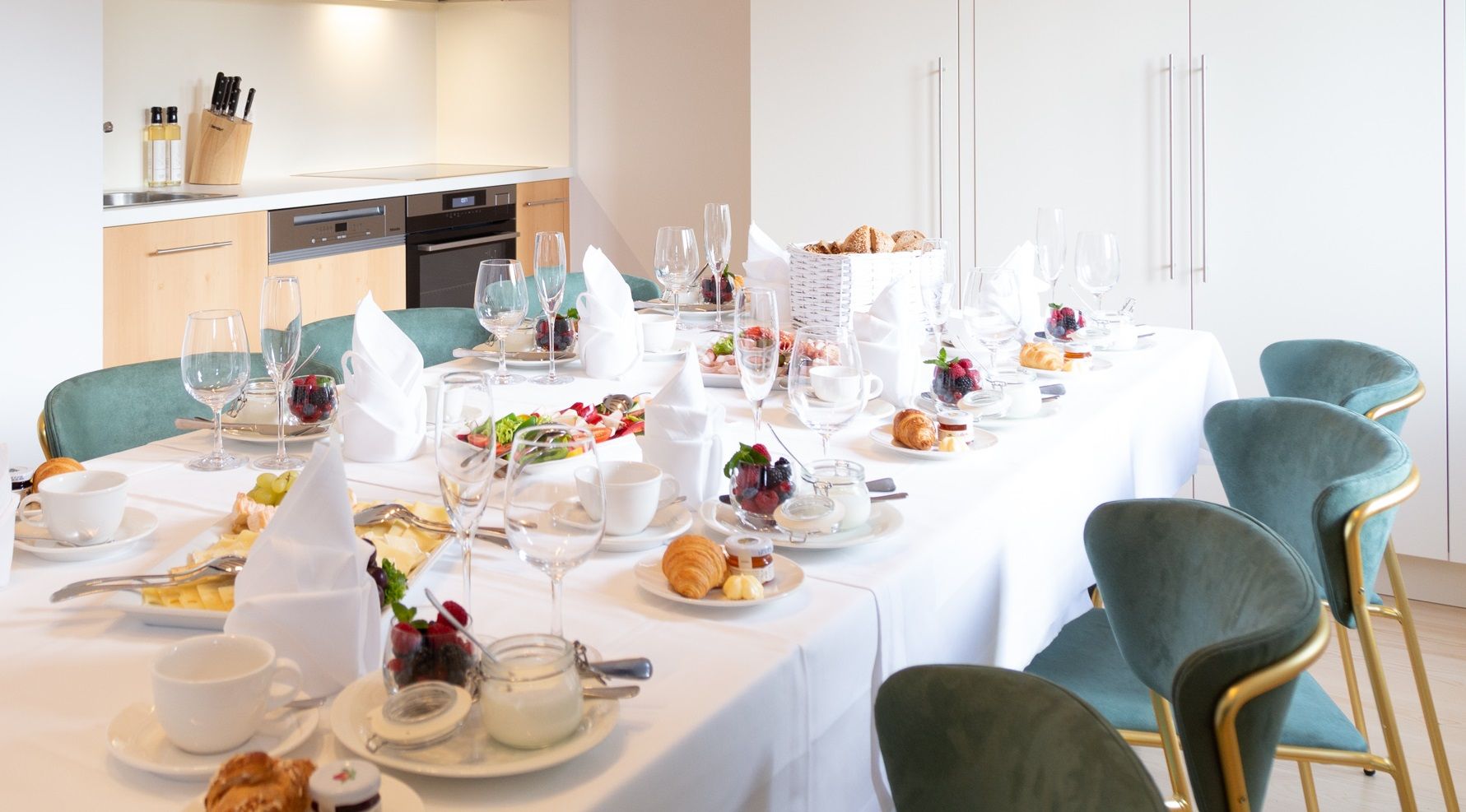 Eleganter Frühstückstisch in moderner Küche mit gedecktem Tisch, Geschirr und Speisen.