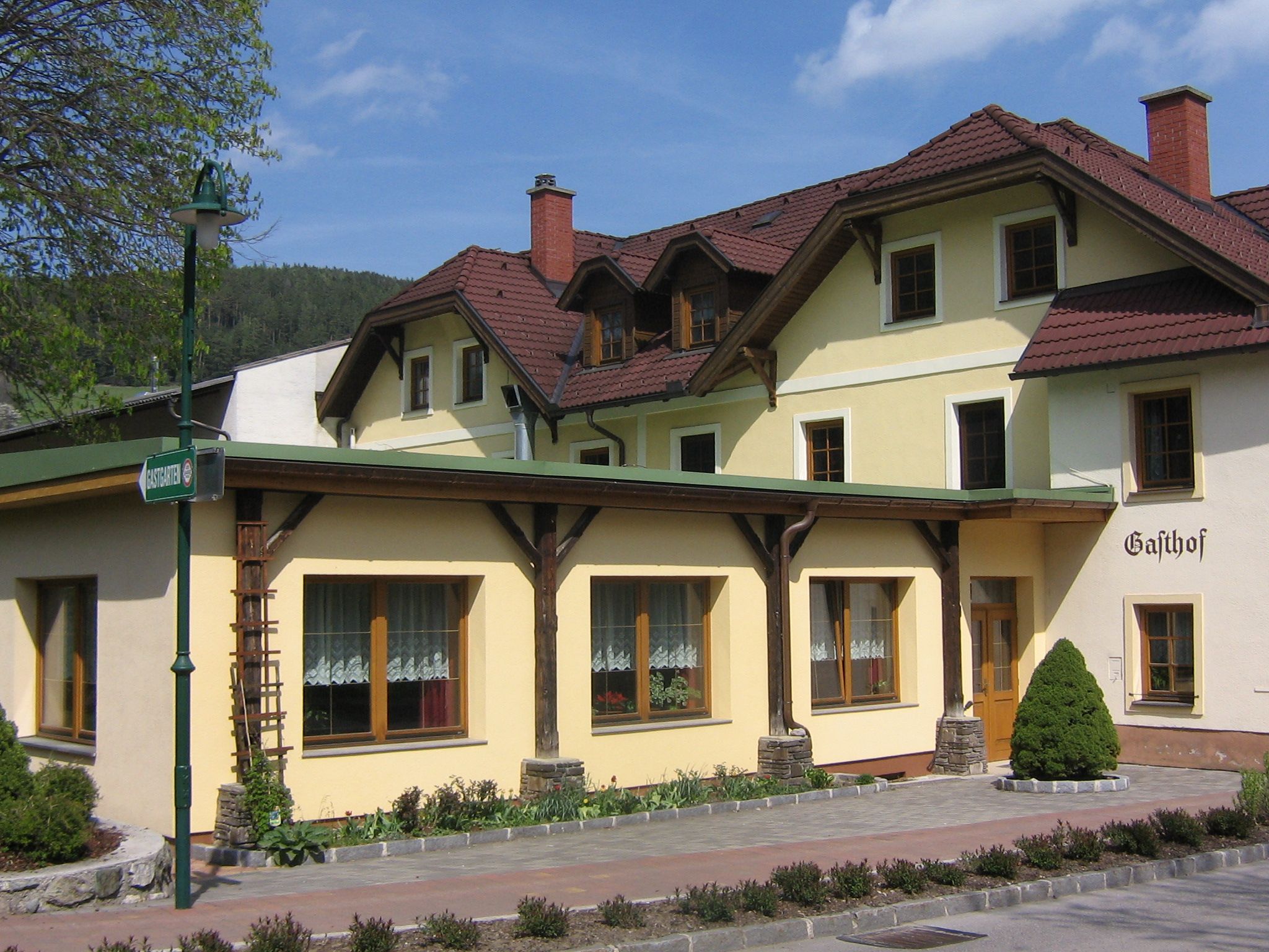 Ein traditioneller Gasthof mit gelber Fassade und roten Dachziegeln.