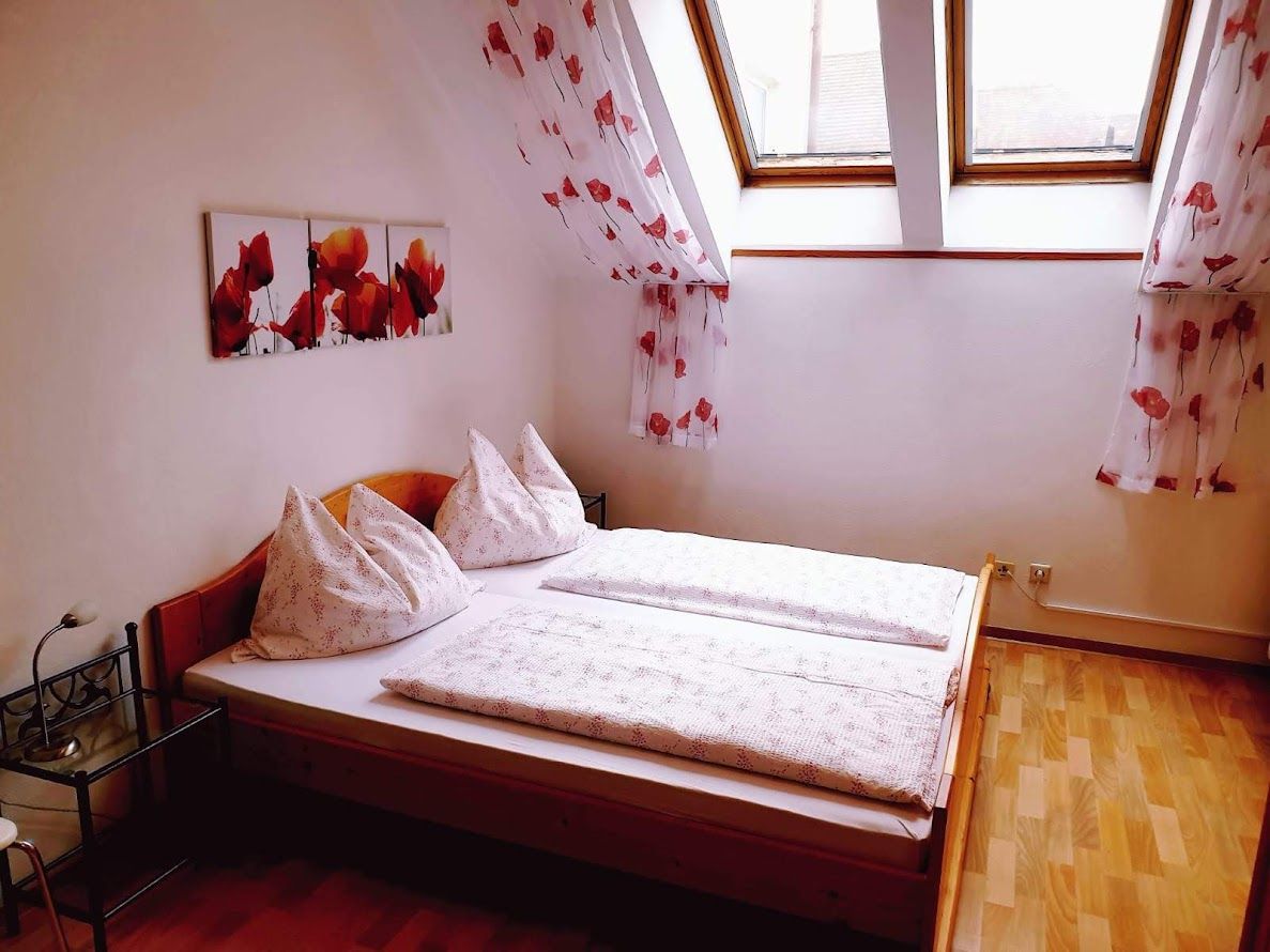 Gemütliches Schlafzimmer mit Doppelbett, Dachfenstern und Mohnblumen-Dekor.