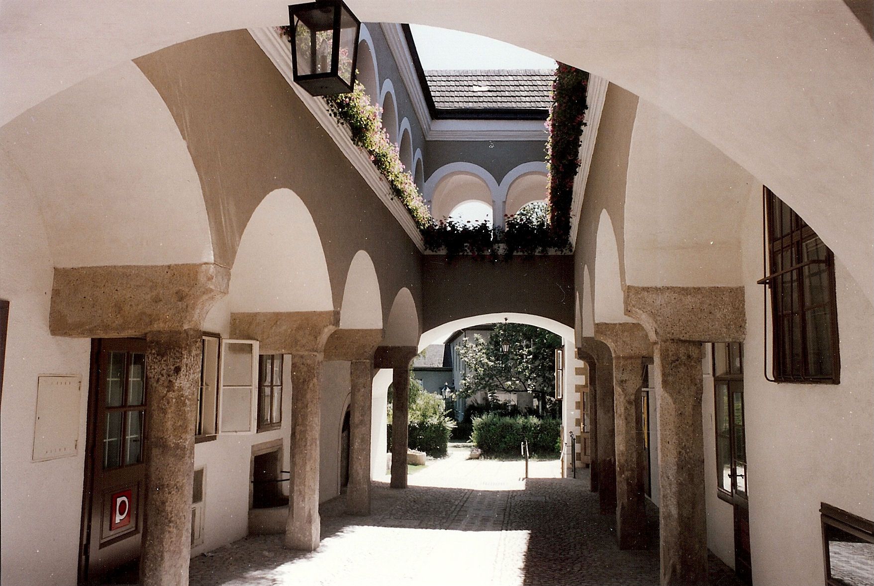 Ein Arkadenhof mit Steinbögen und Blumen im Hafnerhaus.
