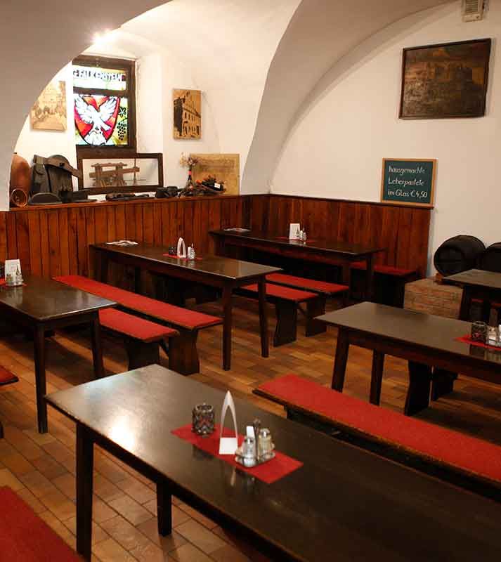 Innenansicht eines traditionellen Wiener Gasthauses mit Holztischen und roten Sitzbänken.