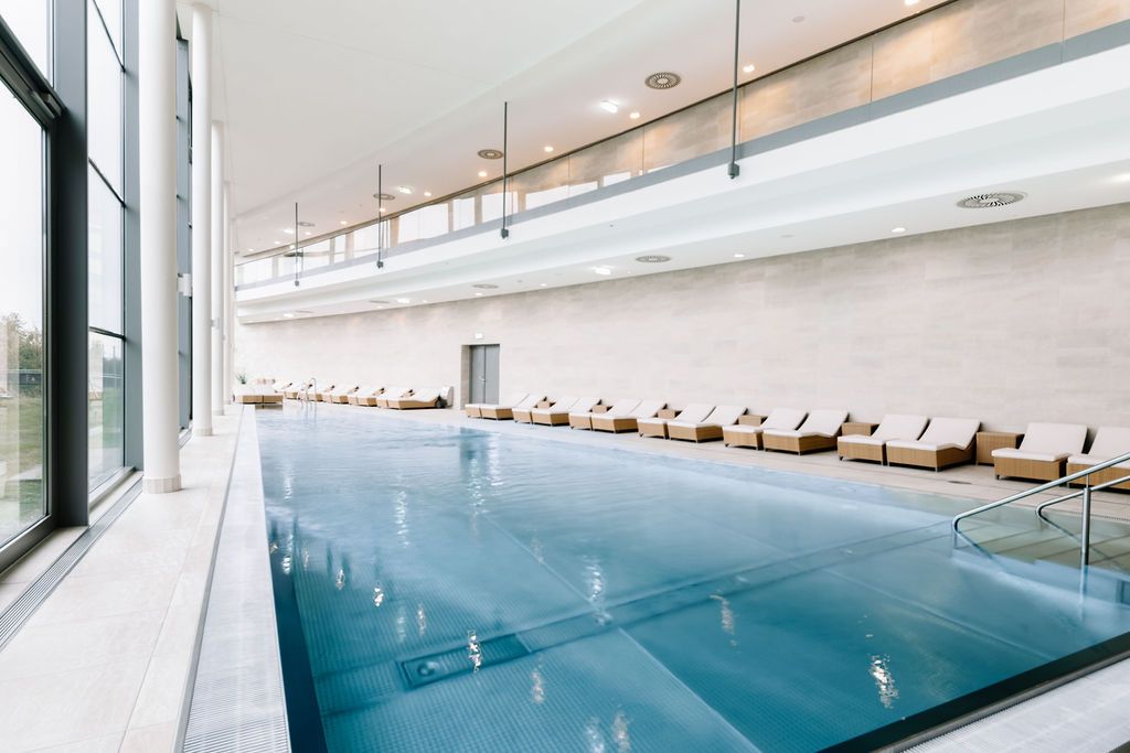 Innenansicht eines modernen Spa-Bereichs mit Pool und Liegestühlen.