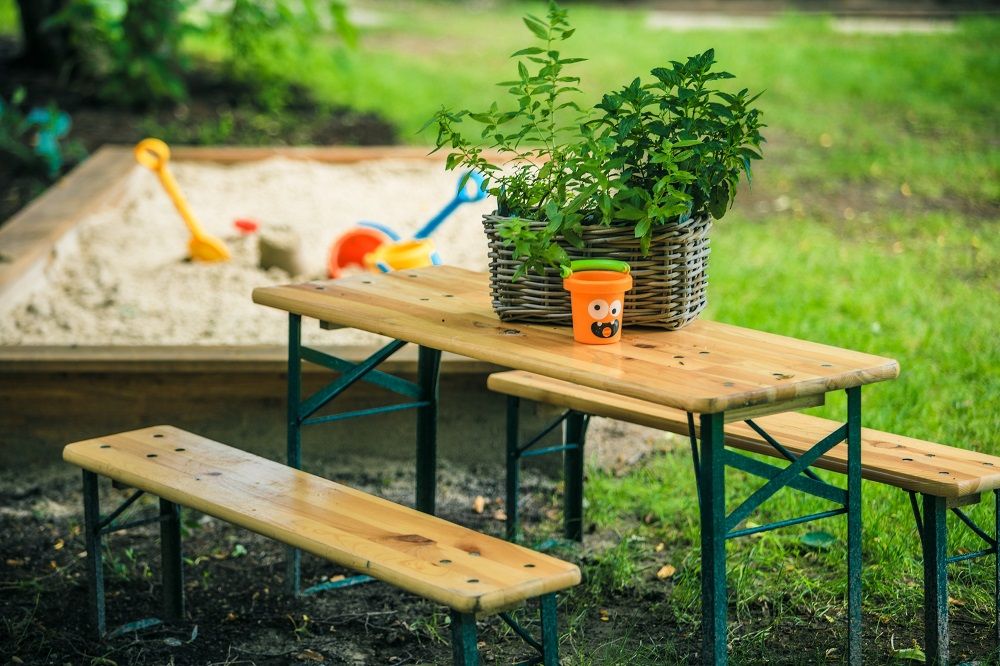 Kinderheurigengarnitur am Sandkasten neben grüner Wiese