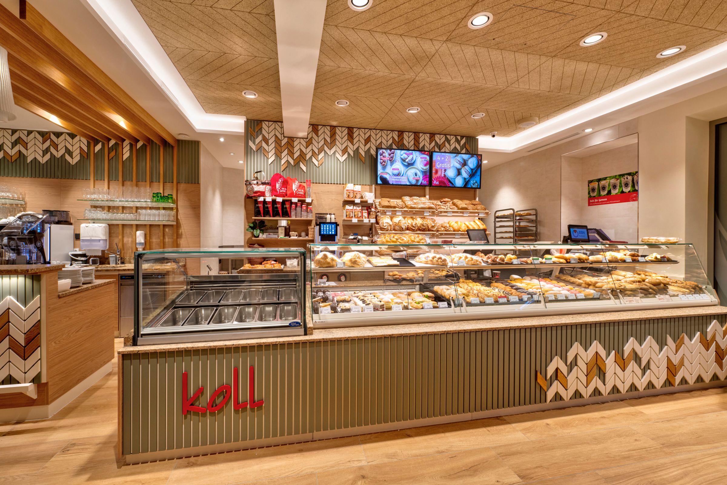 Innenansicht der modernen Bäckerei mit Theke voller Backwaren und Kaffeemaschine.