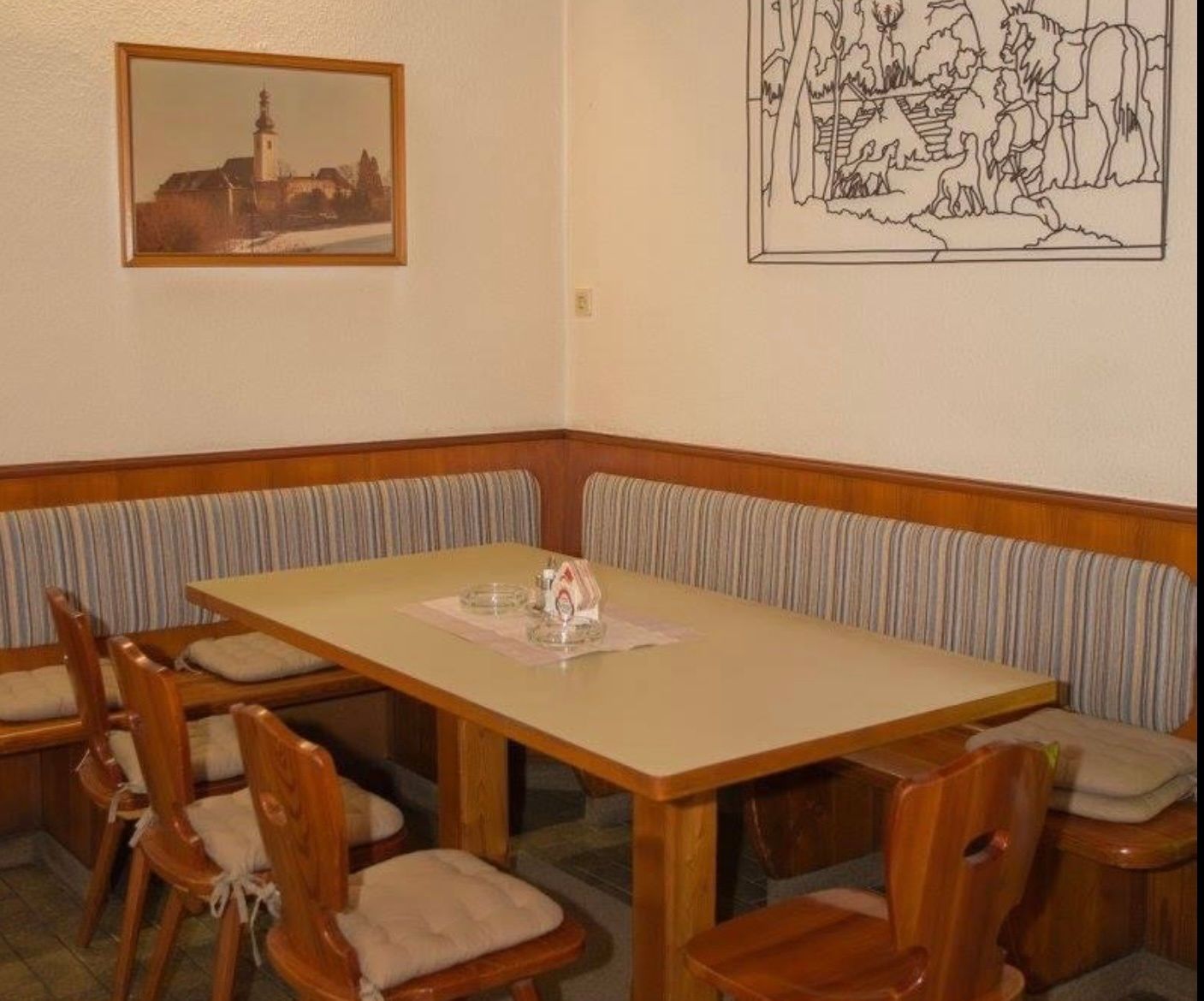 Gemütliche Sitzecke in einem Gasthof mit Holzmöbeln und Wanddekorationen.