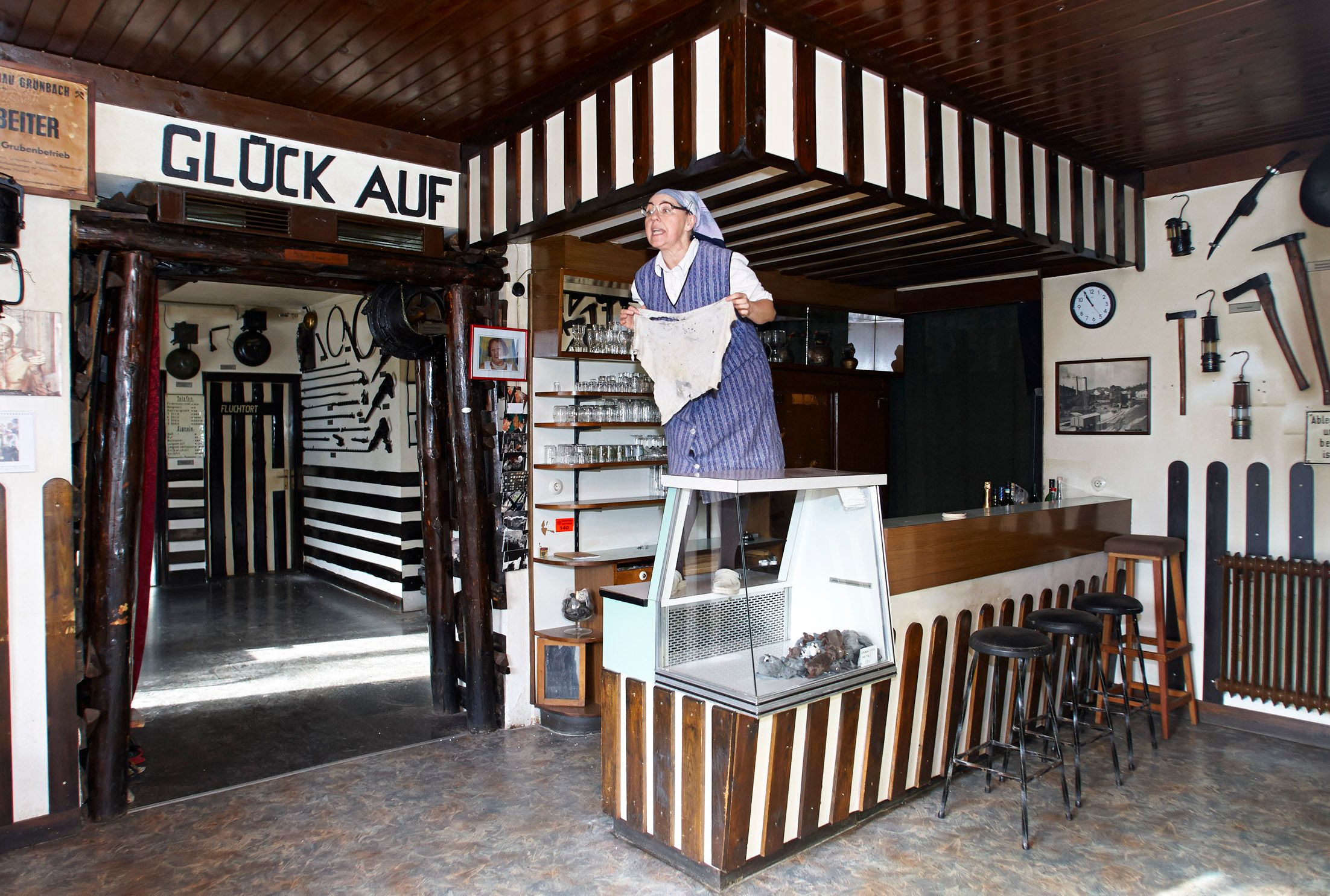 Innenansicht eines Bergbaumuseums mit einer Person in traditioneller Kleidung, die auf einer Theke steht.