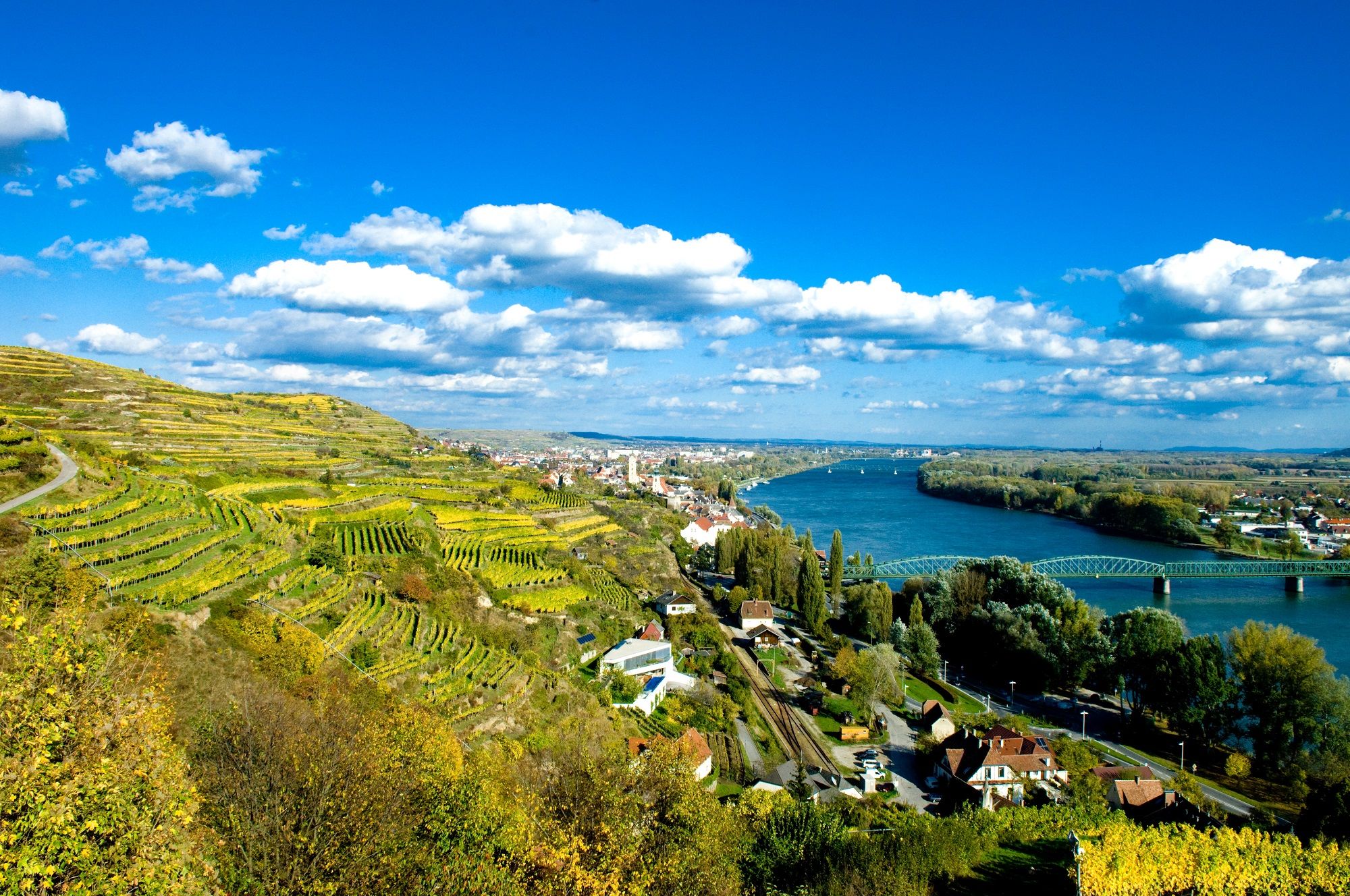 Landschaft mit Weinbergen, Fluss und Brücke in Krems, Österreich.