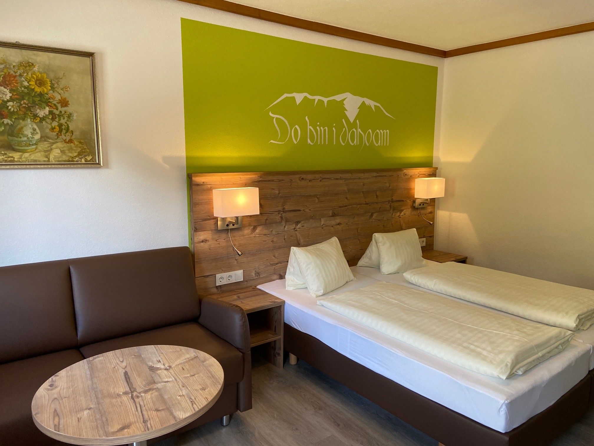 Gemütliches Doppelzimmer mit Holzmöbeln, Sofa, Tisch und Wanddekoration.
