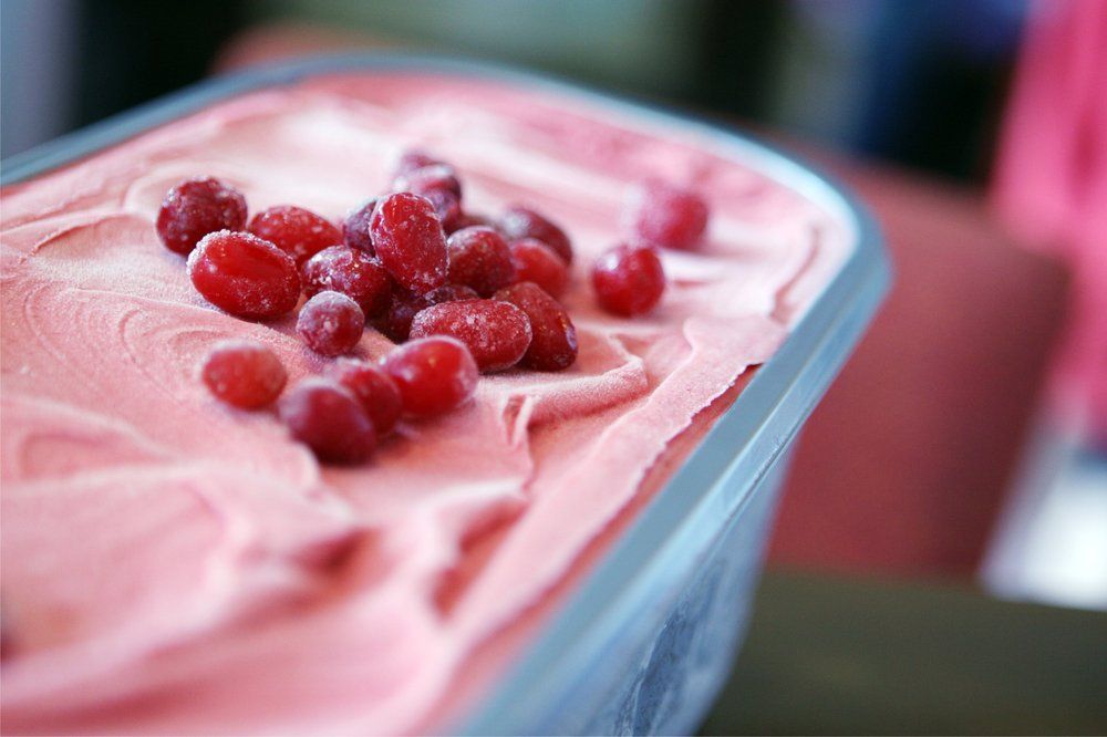 Rosa Eiscreme mit roten Beeren in einer Metallwanne.