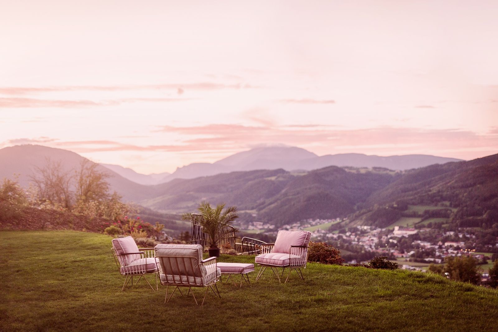 Sitzgruppe auf einer Wiese mit Bergblick bei Sonnenuntergang.