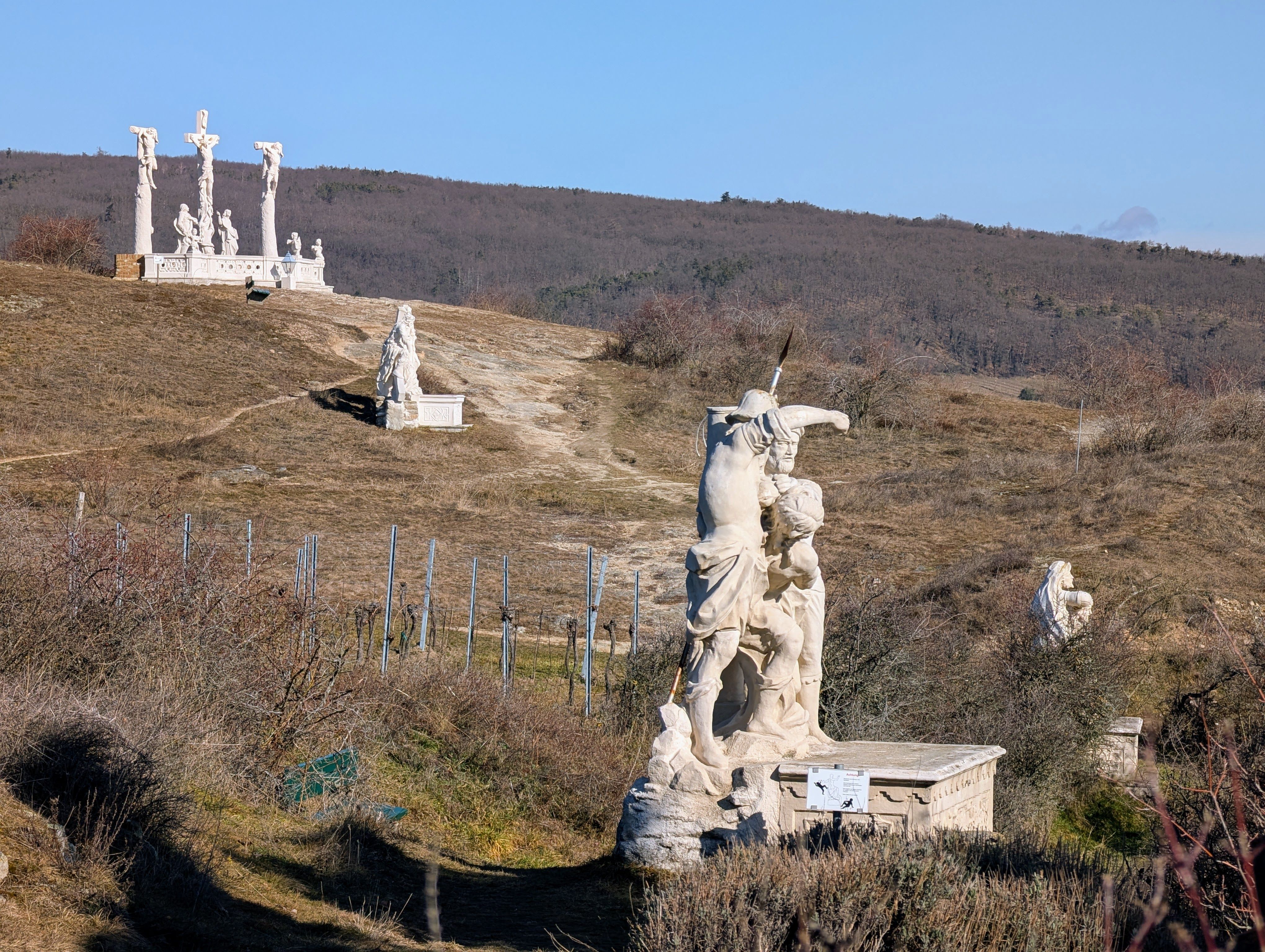 Kalvarienberg mit mehreren religiösen Skulpturen auf einem Hügel unter blauem Himmel.
