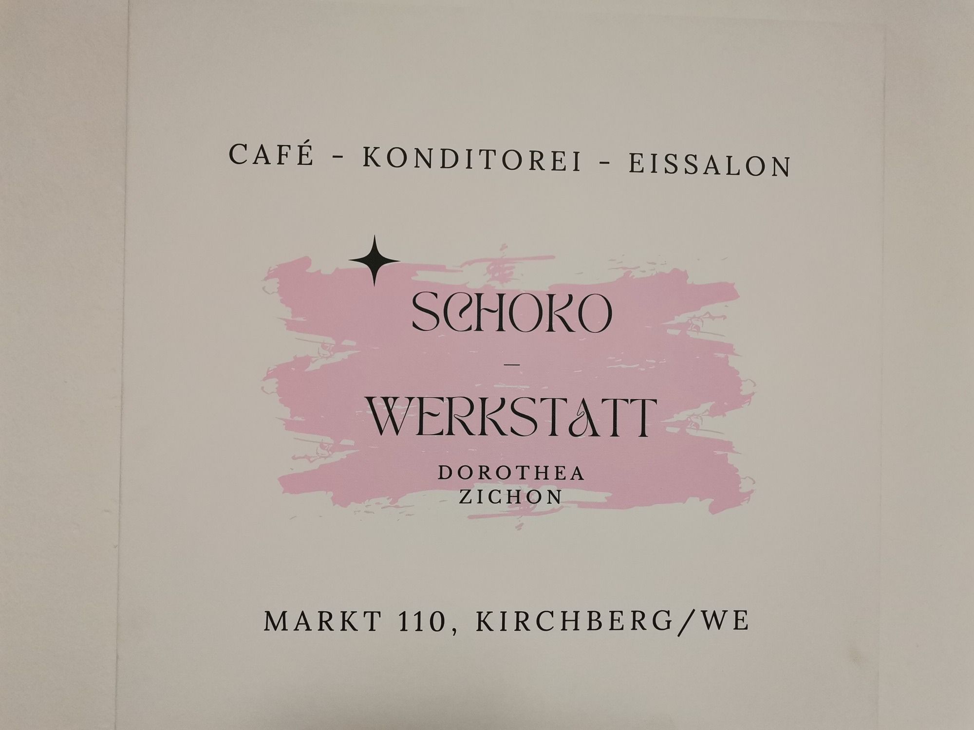 Schild der Schoko-Werkstatt in Kirchberg mit rosa Hintergrund.