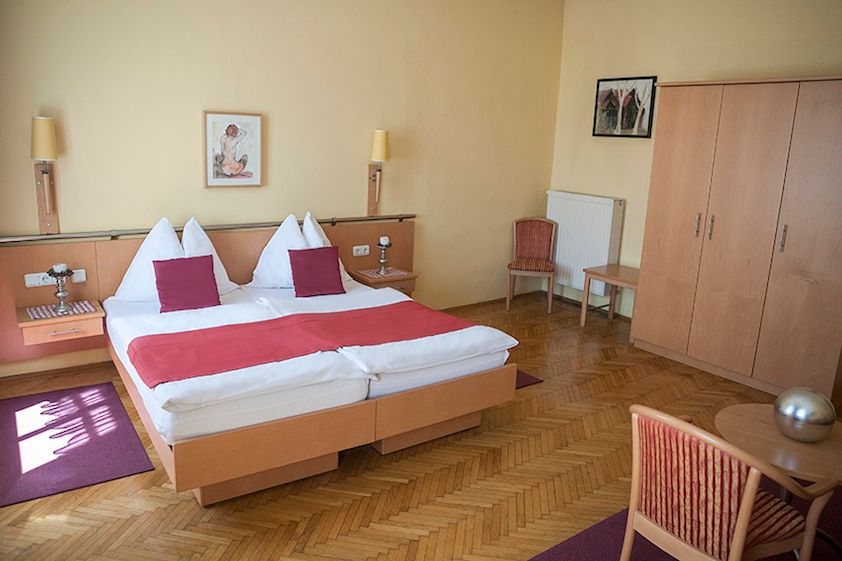 Hotelzimmer mit Doppelbett, Holzmöbeln und roten Akzenten.