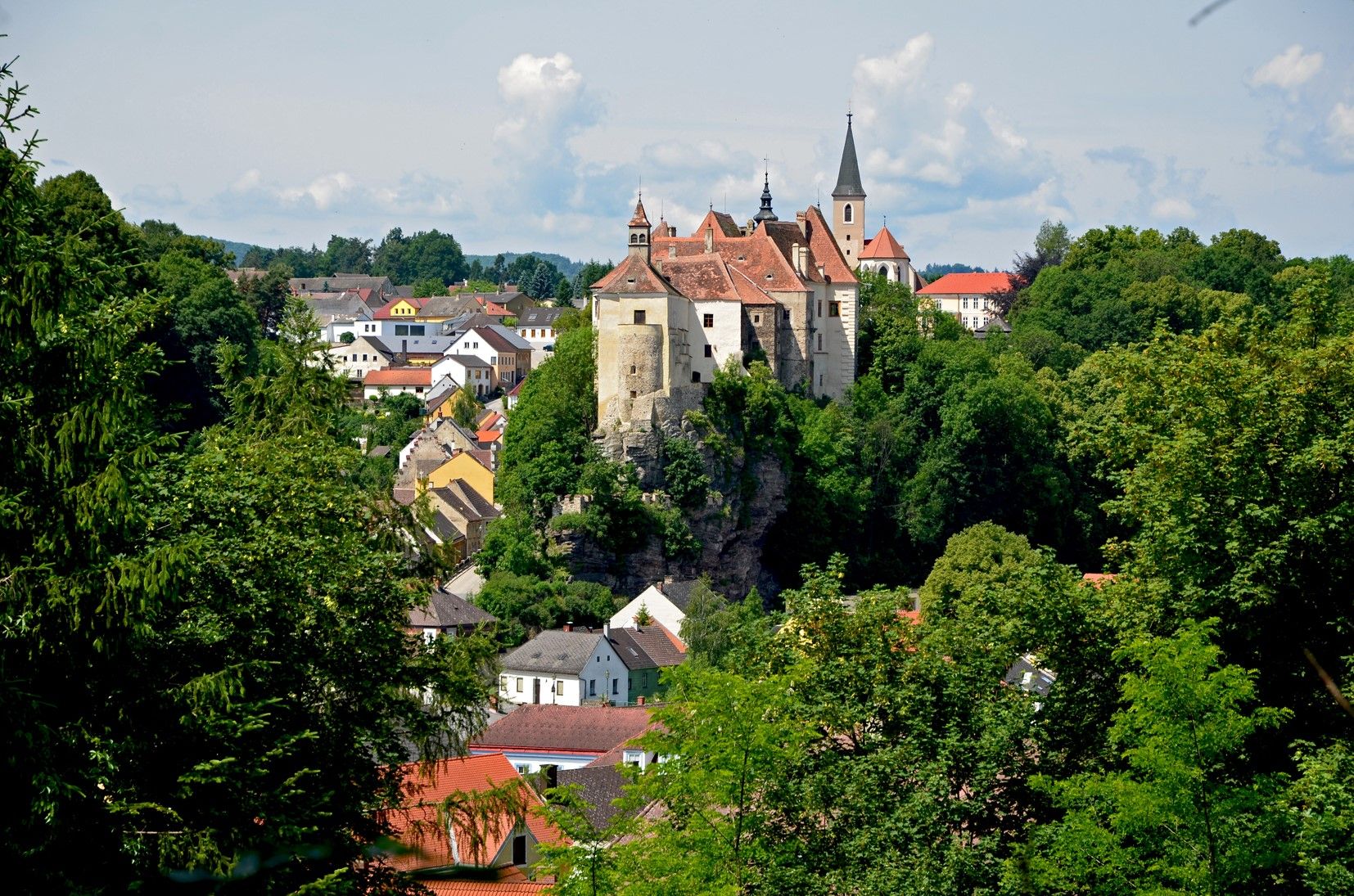 Blick auf die Burg Raabs an der Thaya, umgeben von Bäumen und Häusern.