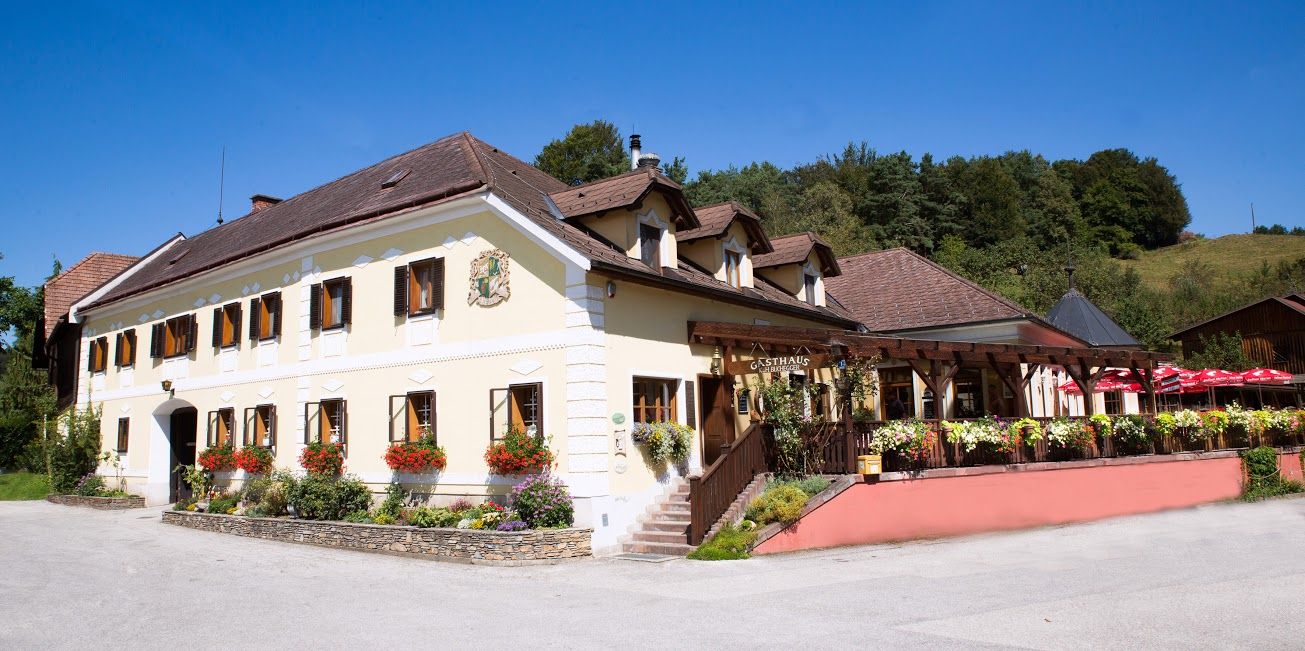 Traditionelles Gasthaus gelber Fassade, vielen Fenstern und Terasse.