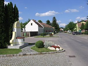 Straße in Mitterndorf an der Fischa mit Häusern und Denkmal.