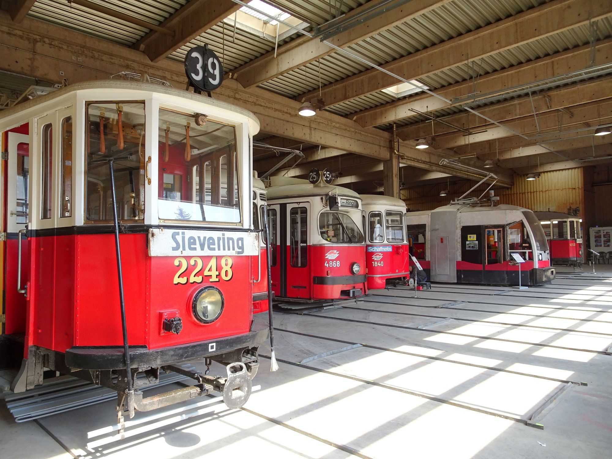 Innenansicht eines Depots mit mehreren historischen Straßenbahnen in Traiskirchen.