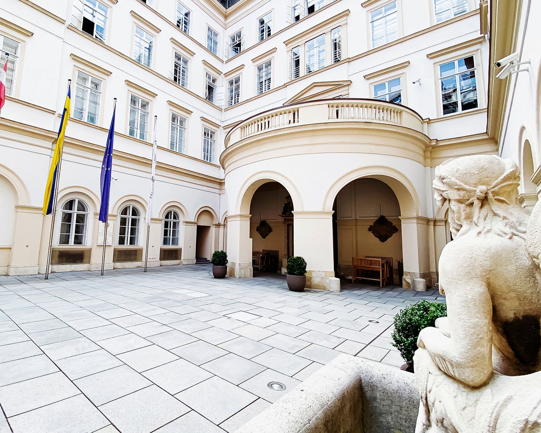 Innenhof des Palais Niederösterreich mit Flaggen und Statue.