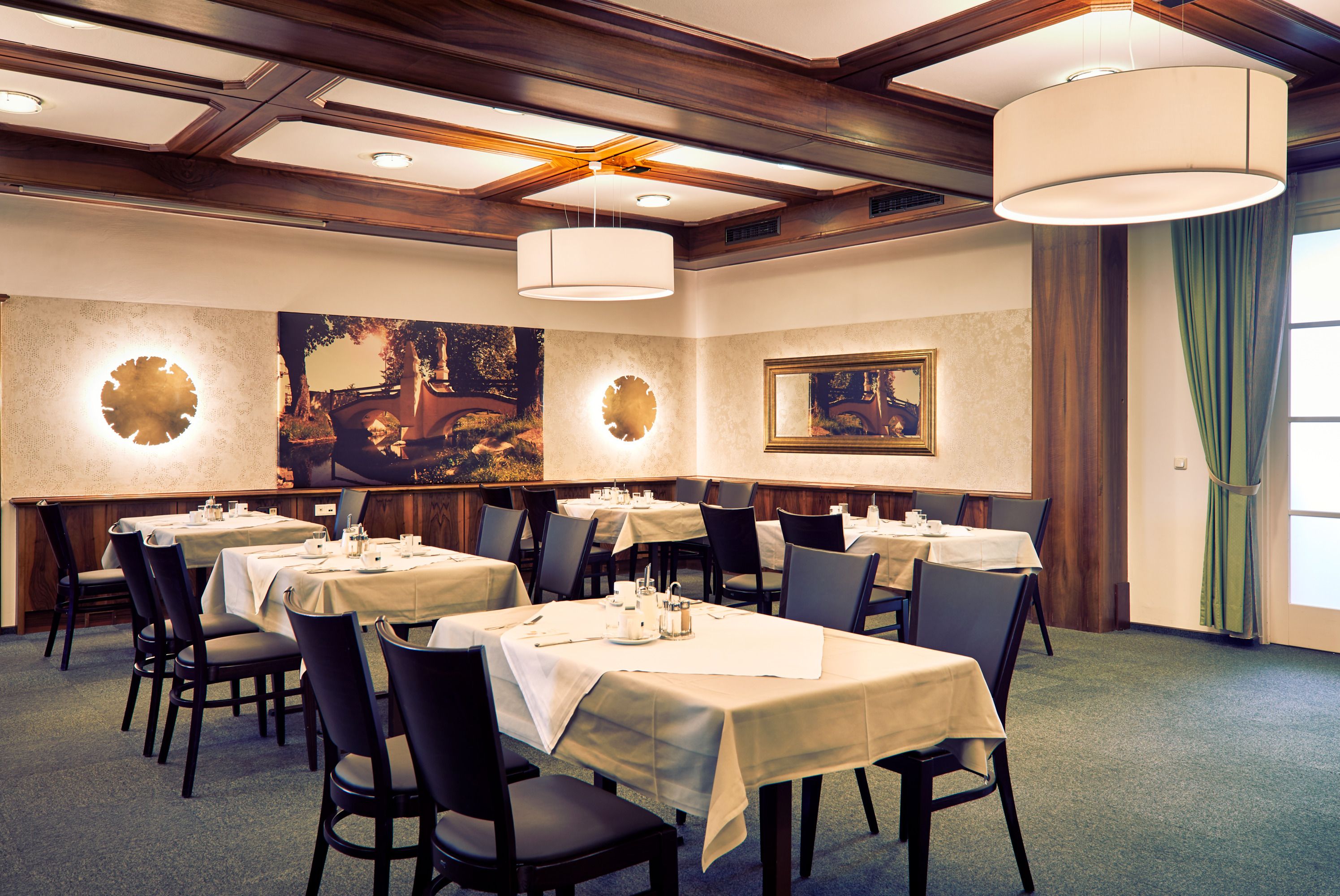 Elegantes Restaurant mit gedeckten Tischen, modernen Leuchten und Wanddekorationen.