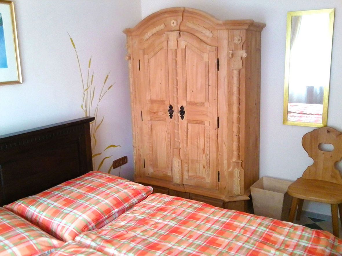 Gästezimmer mit Holzmöbeln und kariertem Bettbezug.
