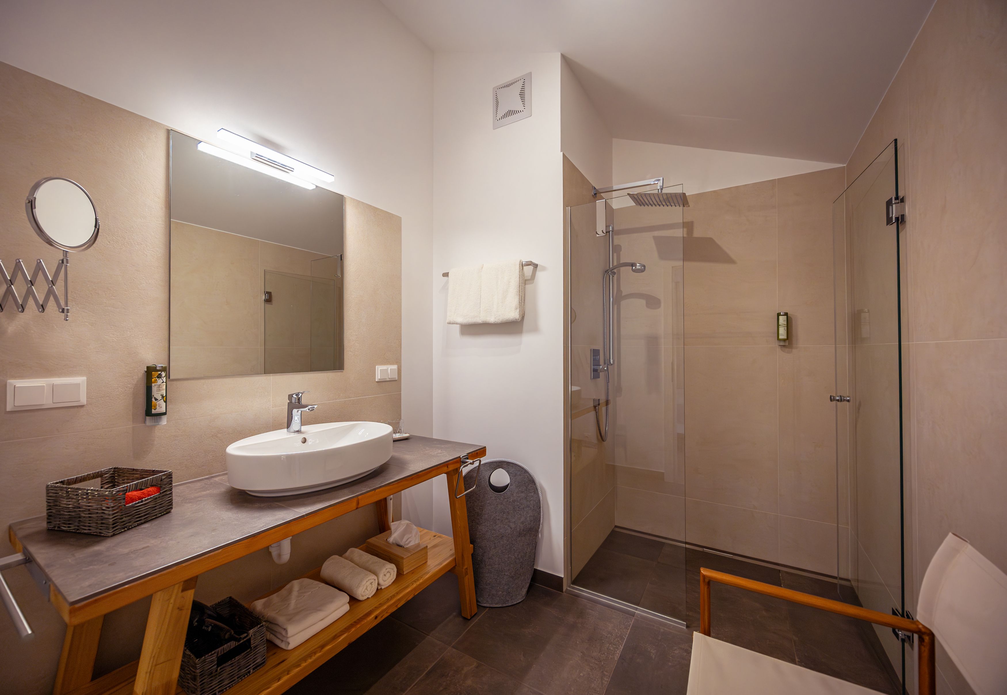 Modernes Badezimmer mit Waschbecken, Spiegel, Dusche und Handtüchern.