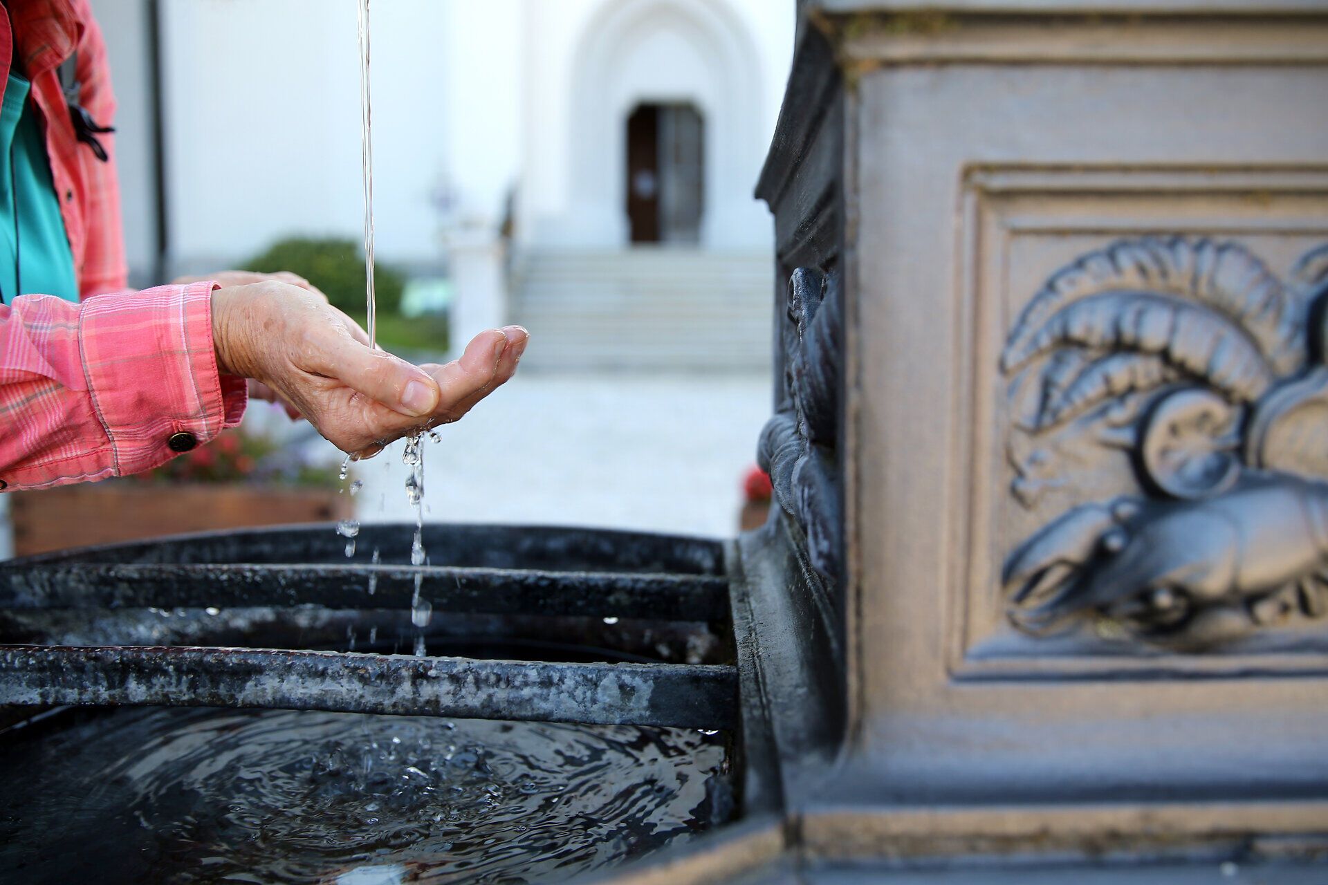 Eine Frau genießt eine erfrischende Trinkpause an einem historischen Brunnen, umgeben von der malerischen Natur des Mostviertels. Das sanfte Plätschern des Wassers und die frische Bergluft laden dazu ein, die Seele baumeln zu lassen und die Schönheit der Umgebung zu erleben.