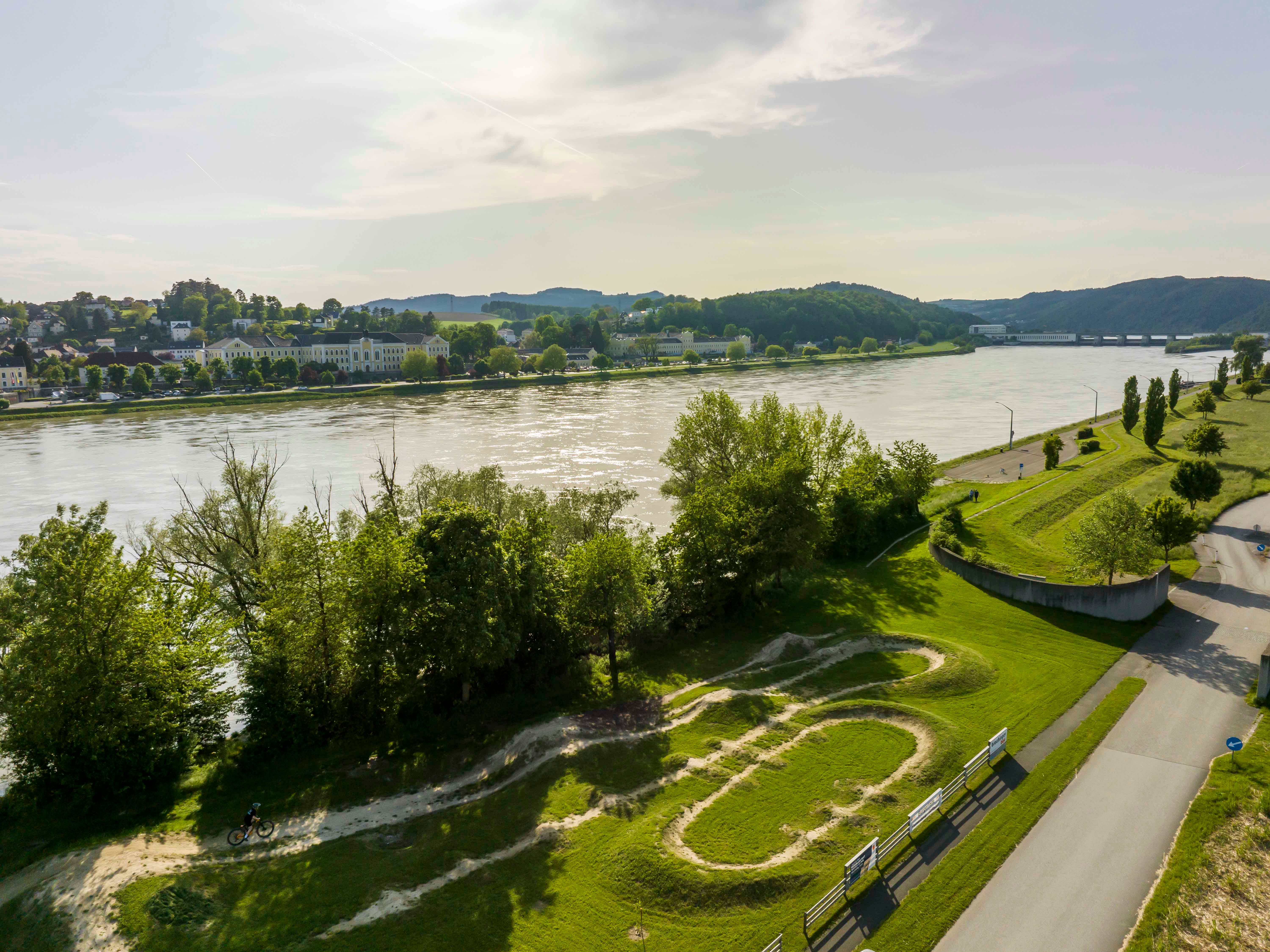Luftaufnahme der Bikearena Persenbeug-Gottsdorf mit Fluss und umliegender Landschaft.