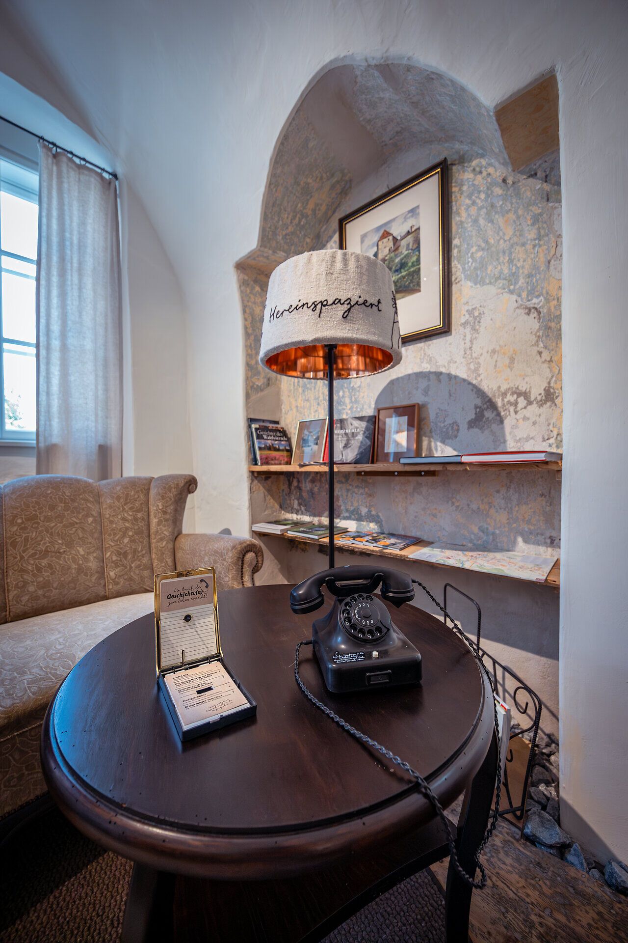 Ein einladendes Ambiente erwartet die Gäste in den Stadt-Lofts, wo historische Elemente auf modernen Komfort treffen. Der nostalgische Telefonapparat und die stilvolle Lampe schaffen eine gemütliche Atmosphäre, die zum Verweilen einlädt. Hier können Besucher die Ruhe genießen und sich auf ihre Erkundungstouren im Waldviertel vorbereiten.