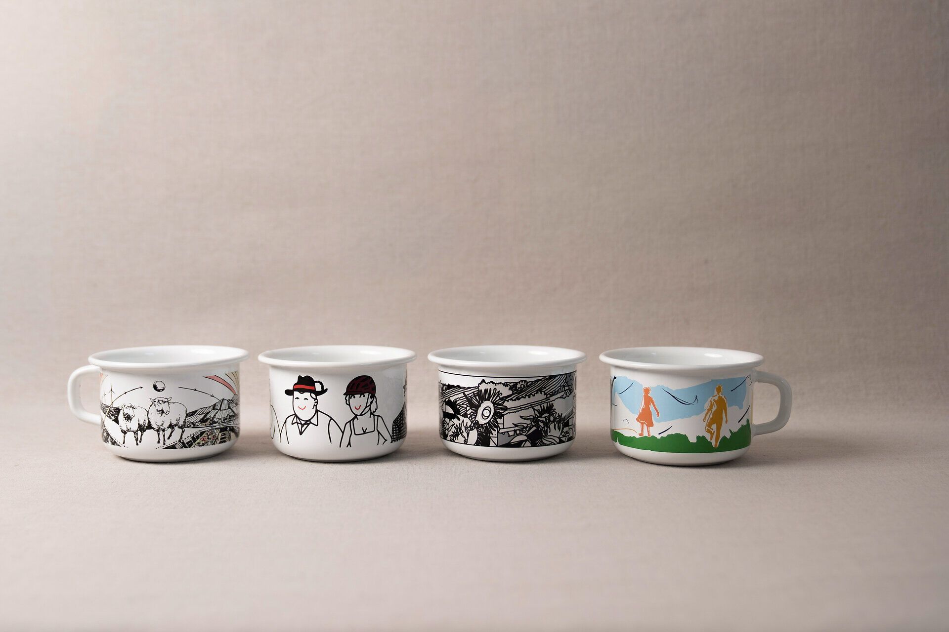 4 von Küstler:innen gestaltete Tassen aus Email von der Firma Riess mit aus Niederösterreich inspirierten Motiven. 