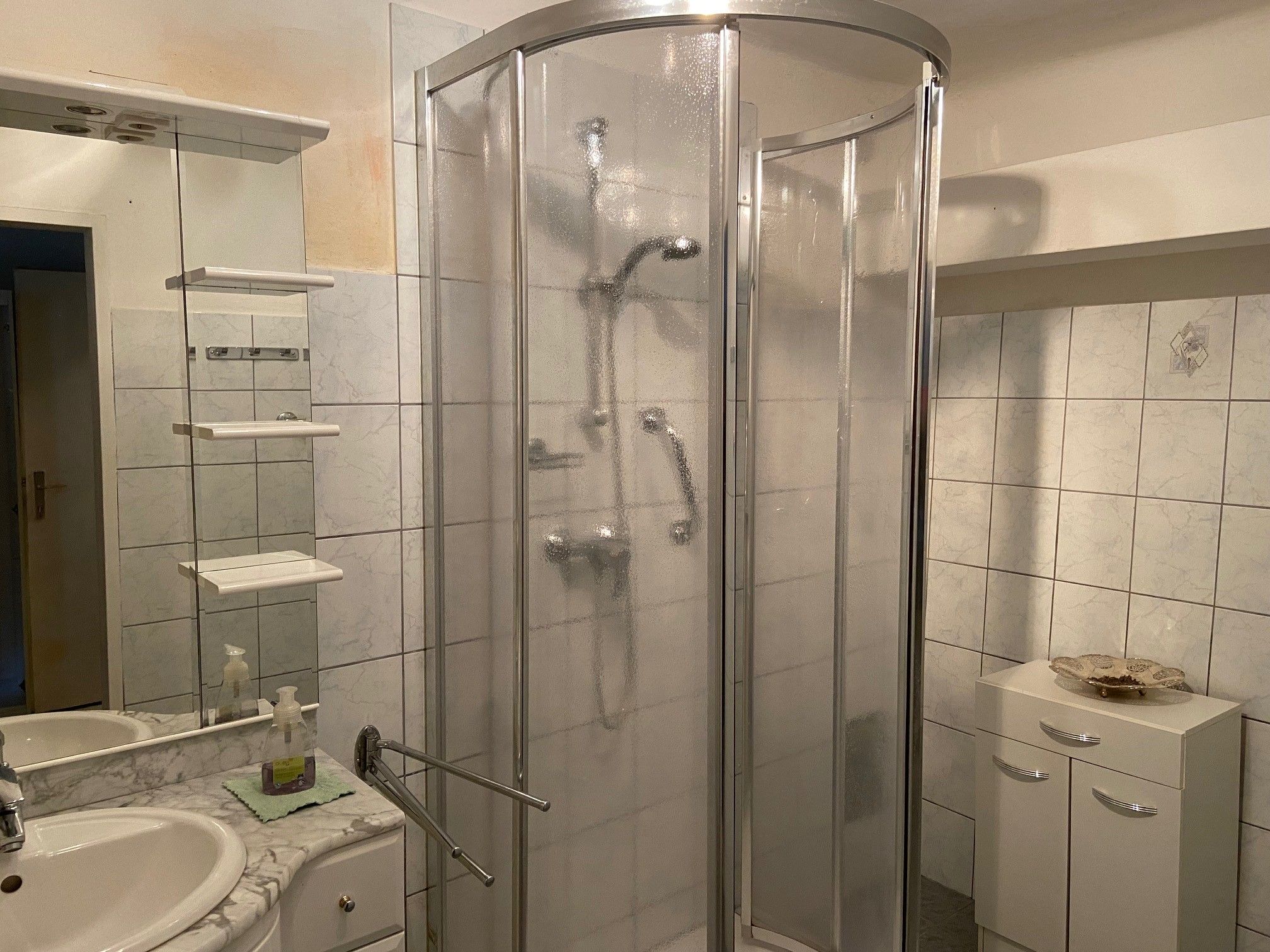 Badezimmer mit Dusche, Waschbecken und Spiegel.