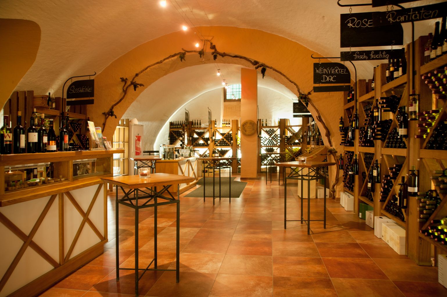 Innenansicht einer Vinothek mit Weinregalen und Tischen.