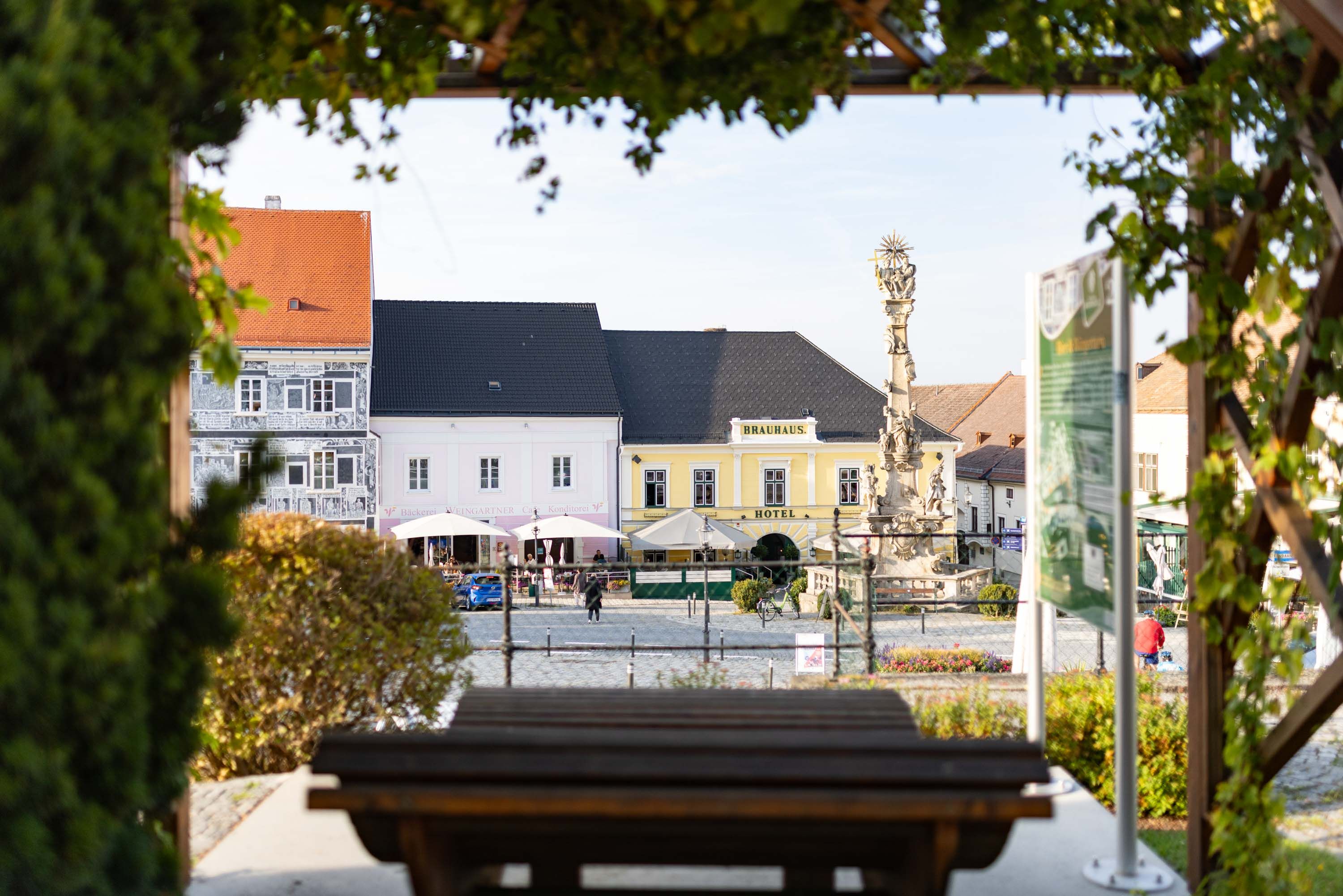 Blick auf ein gelbes Gebäude mit der Aufschrift 'Brauhotel' und einem Platz mit einer Statue im Vordergrund.