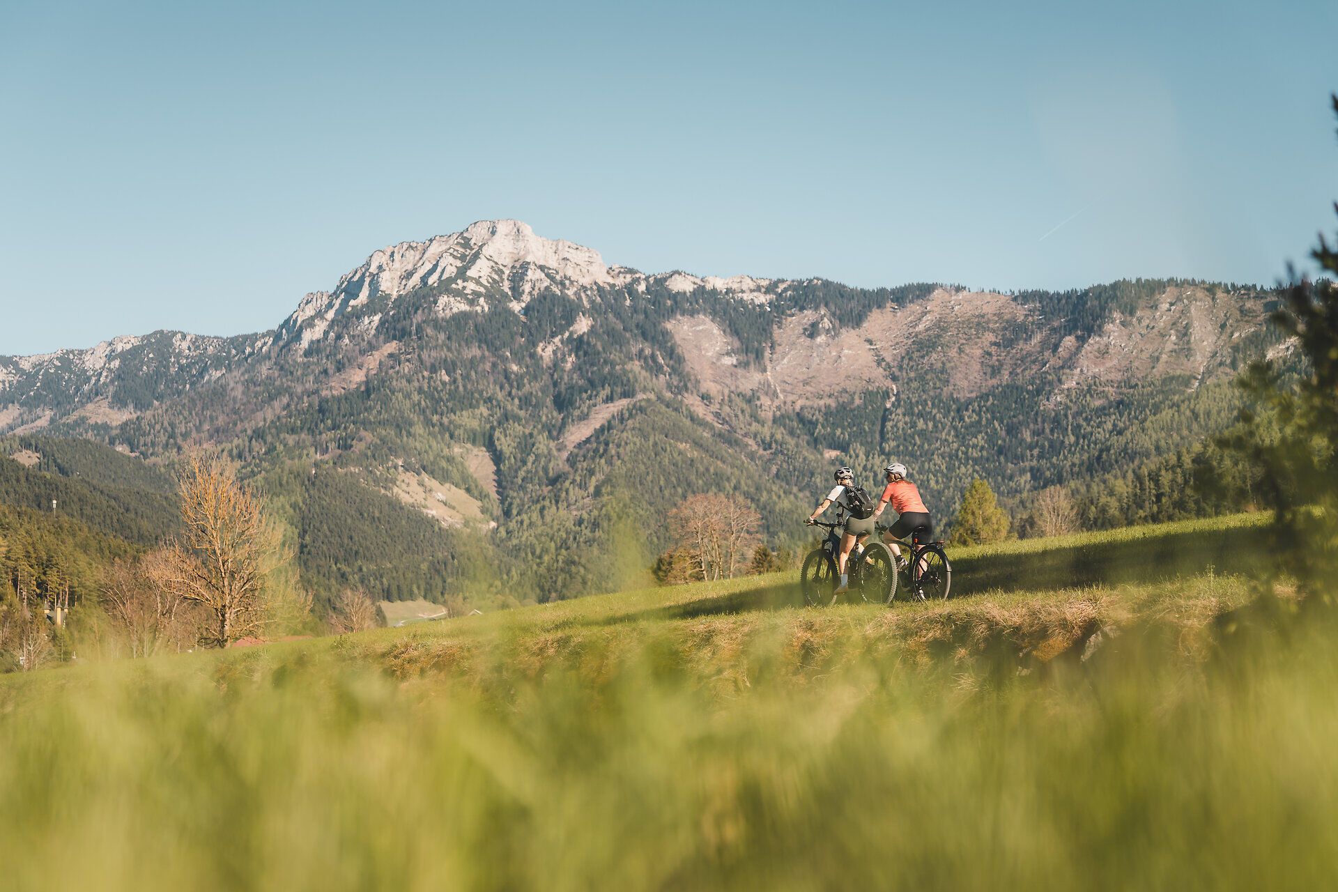 Zwei Radfahrerinnen auf dem Traisental-Radweg, Bergpanorama im Hintergrund.