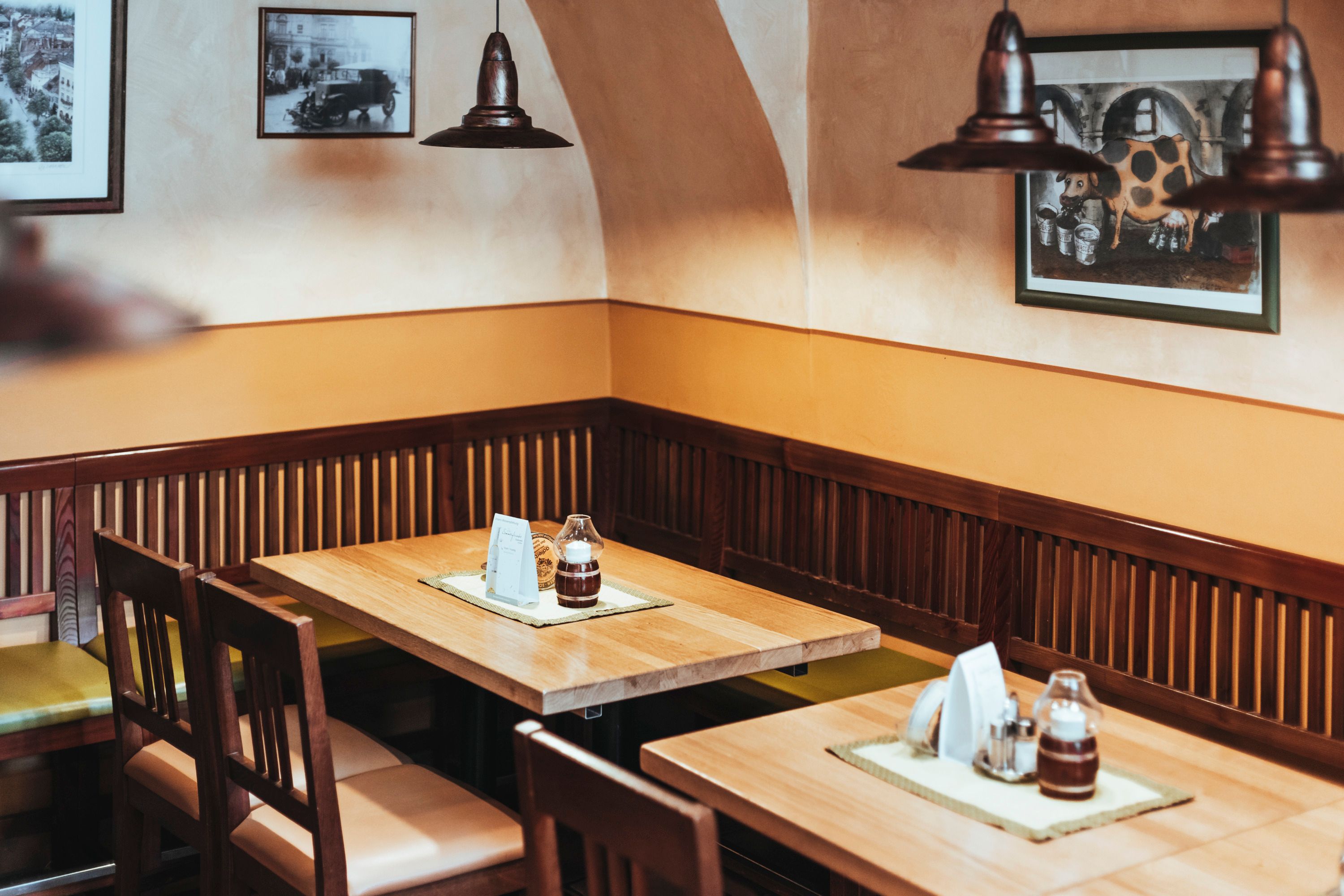 Gemütliche Sitzecke in einem Restaurant mit Holztischen und -stühlen, dekoriert mit Bildern an der Wand.