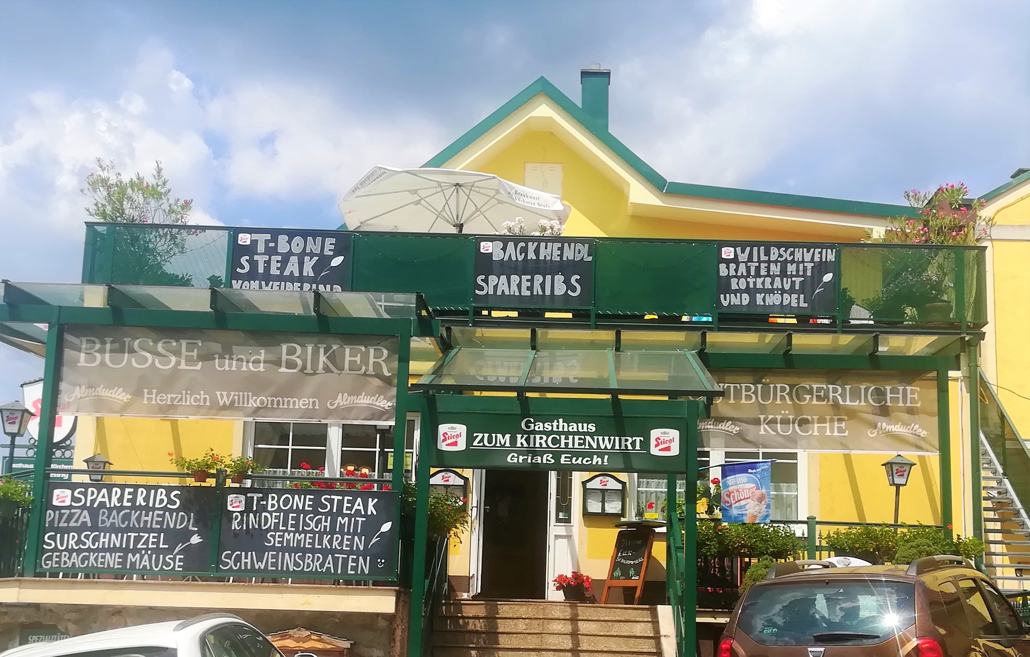 Gelbes Gasthaus mit grüner Beschilderung von Tagesangeboten